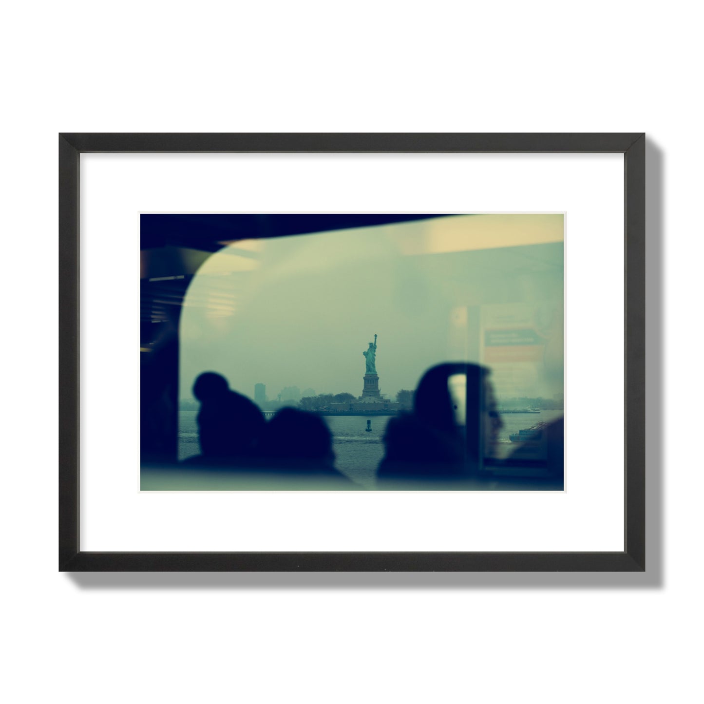 Fine art photograph of passengers silhouetted on a crowded ferry with the Statue of Liberty in the background, archival pigment print, medium size, black frame.