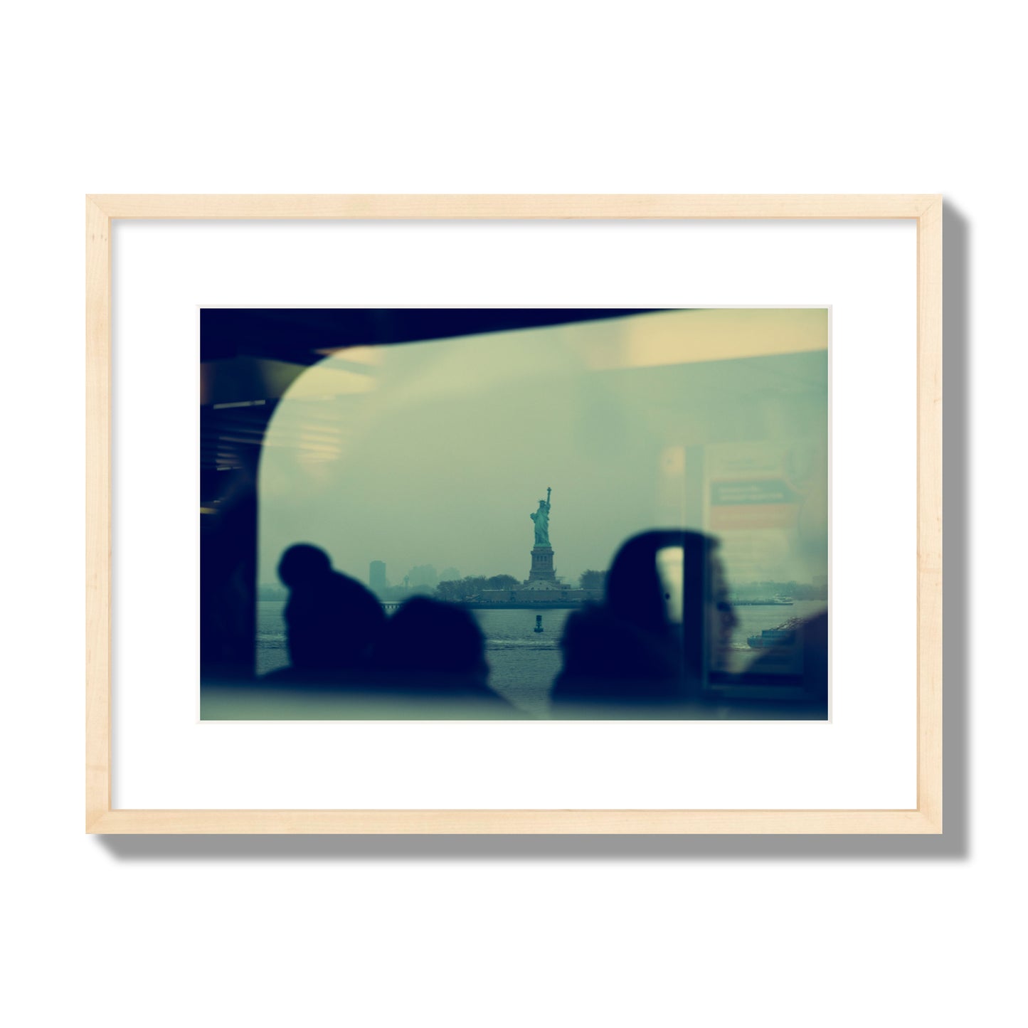 Fine art photograph of passengers silhouetted on a crowded ferry with the Statue of Liberty in the background, archival pigment print, medium size, natural wood frame.