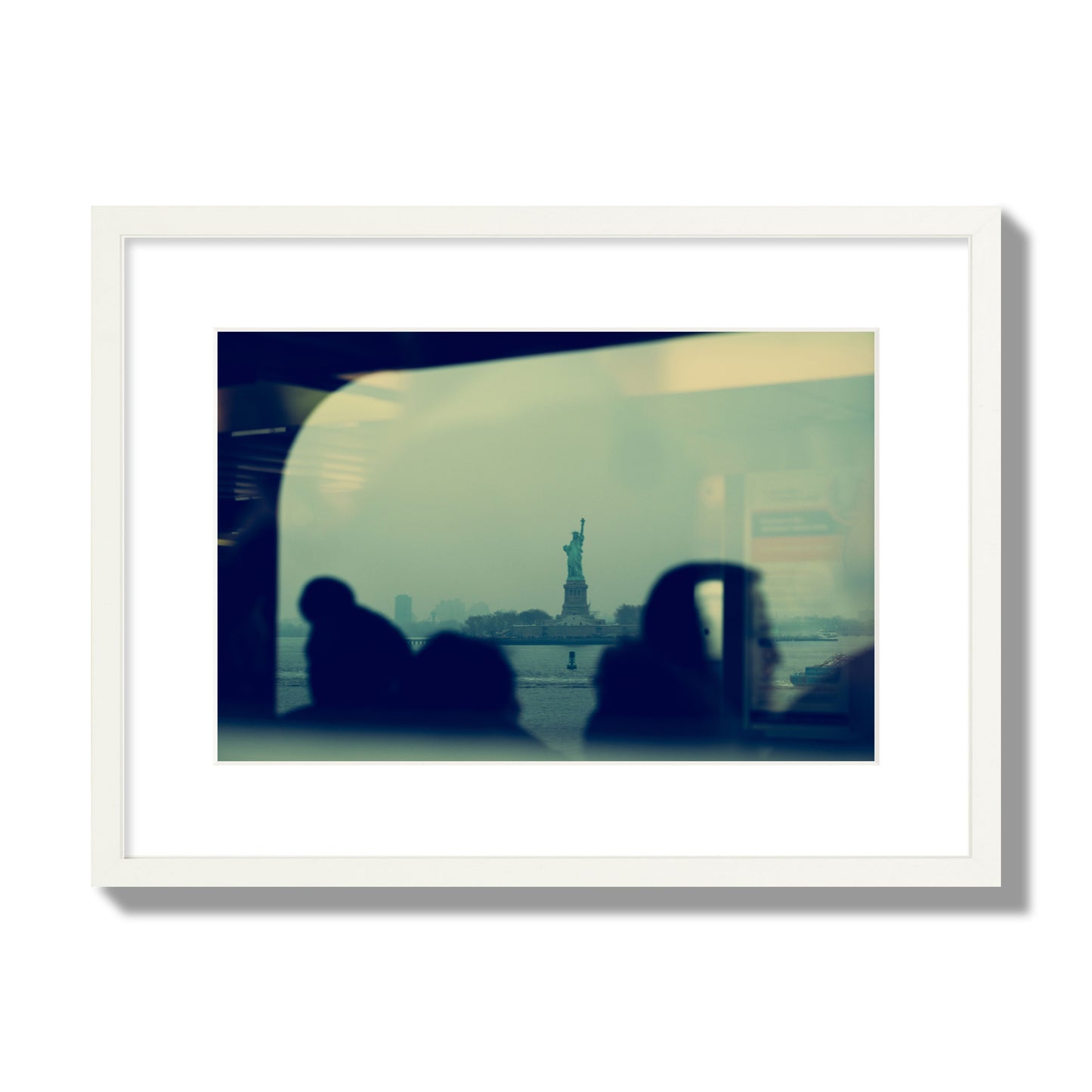 Fine art photograph of passengers silhouetted on a crowded ferry with the Statue of Liberty in the background, archival pigment print, medium size, white frame.