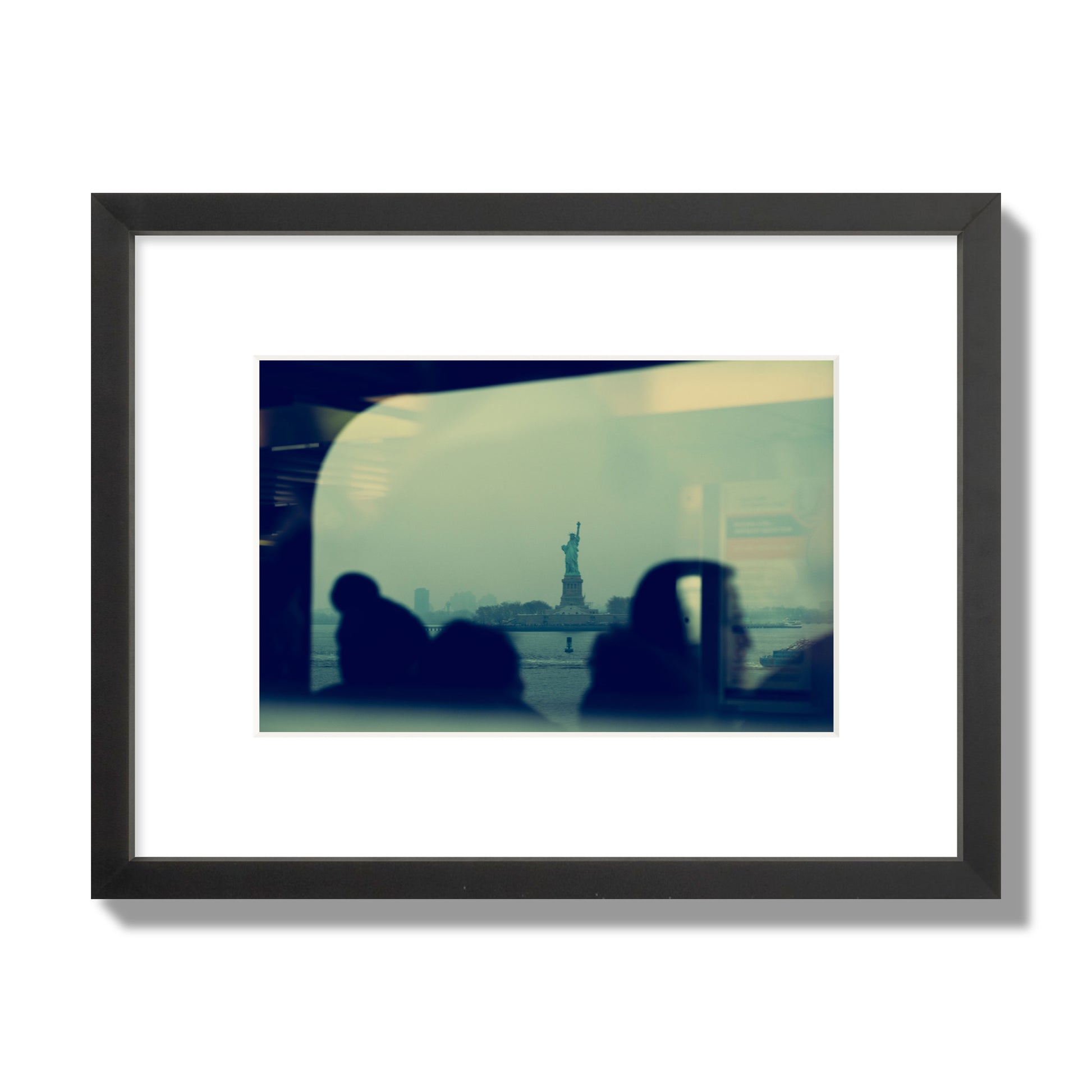 Fine art photograph of passengers silhouetted on a crowded ferry with the Statue of Liberty in the background, archival pigment print, small size, black frame.