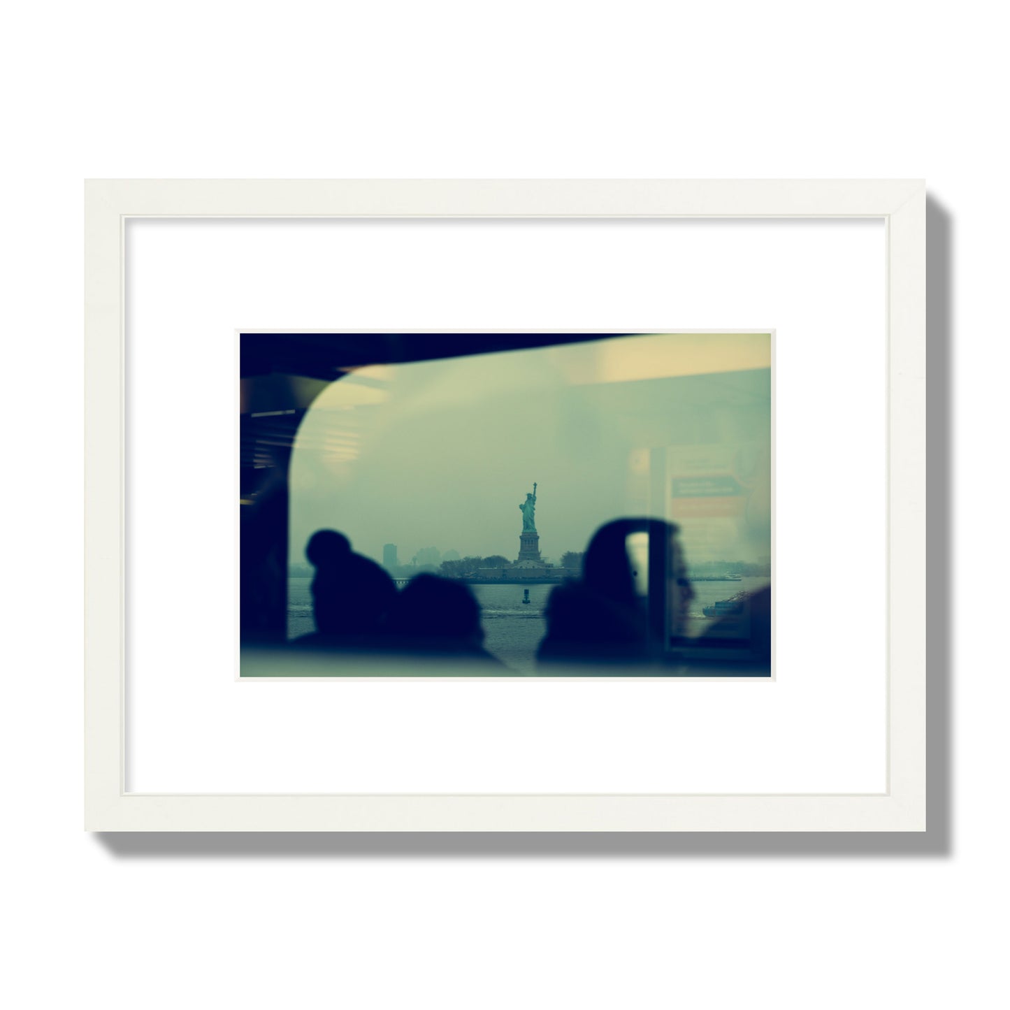 Fine art photograph of passengers silhouetted on a crowded ferry with the Statue of Liberty in the background, archival pigment print, small size, white frame.