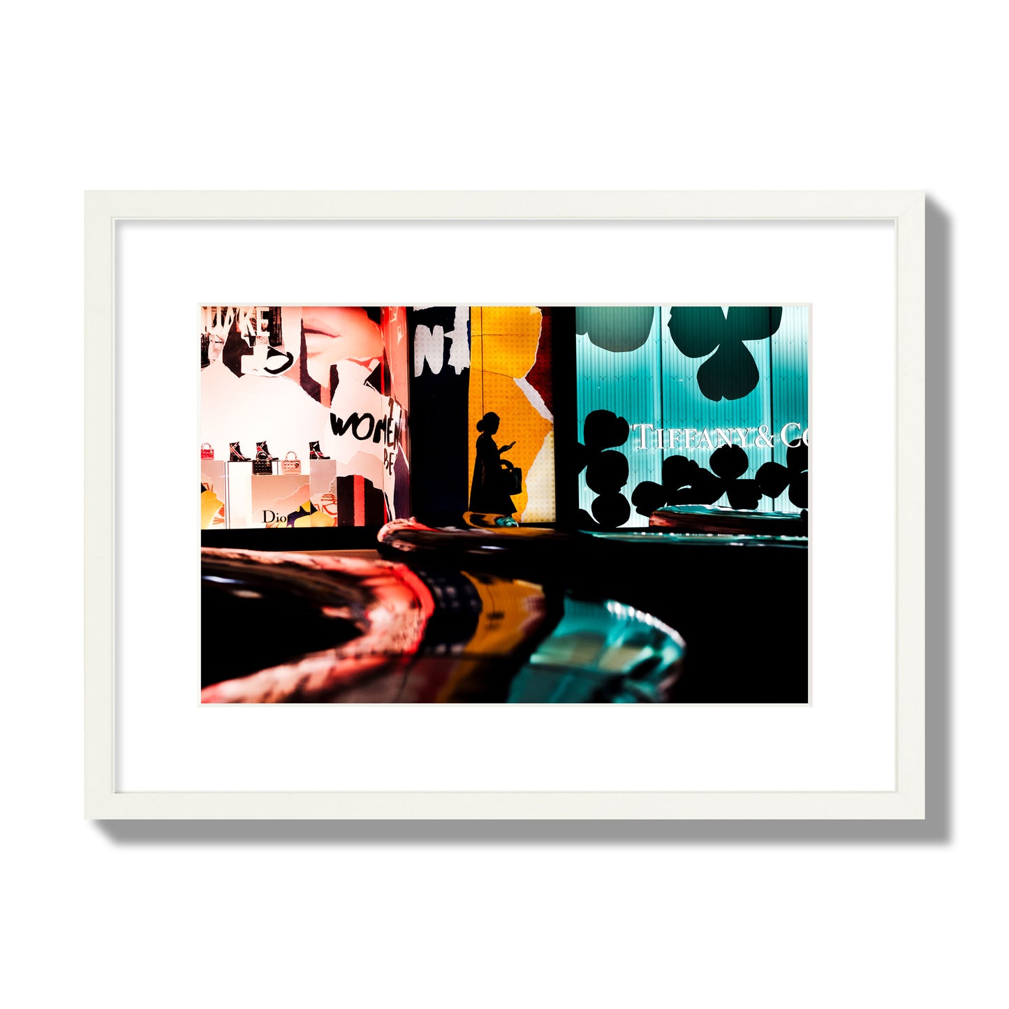 Fine art photograph of a woman’s silhouette walking past vibrant neon store signs, archival pigment print, medium size, white frame.