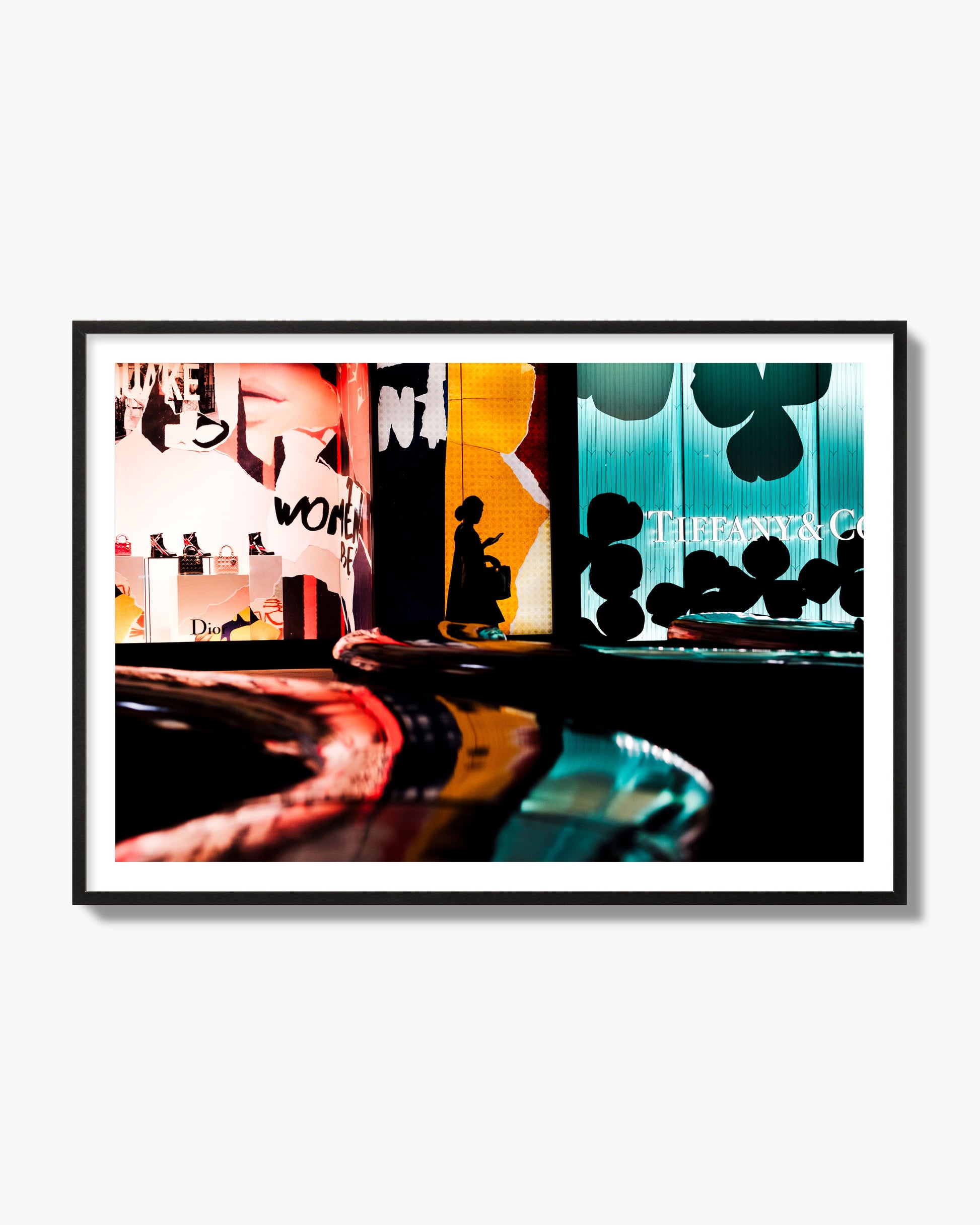 Fine art photograph of a woman’s silhouette walking past vibrant neon store signs, archival pigment print, black frame.