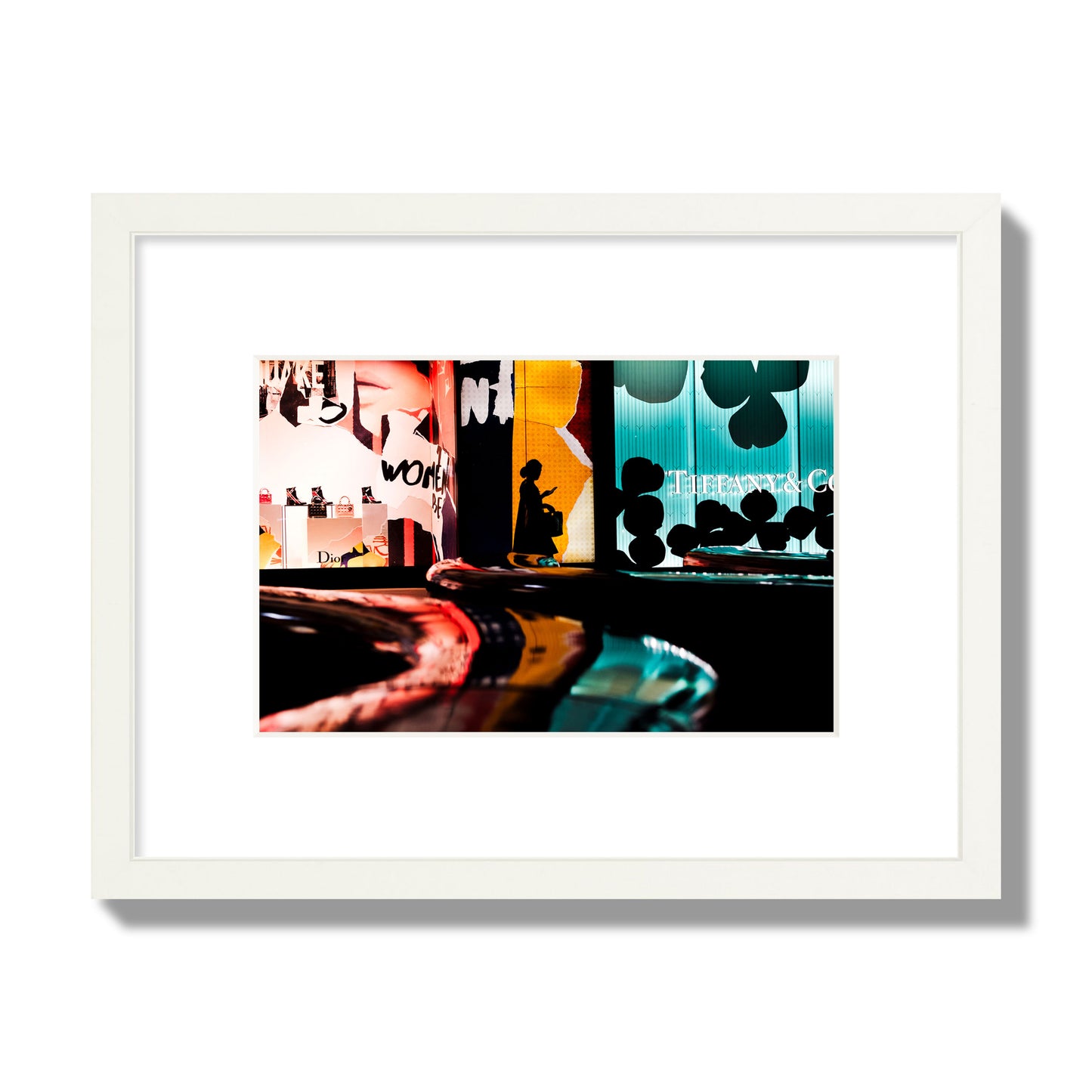 Fine art photograph of a woman’s silhouette walking past vibrant neon store signs, archival pigment print, small size, white frame.