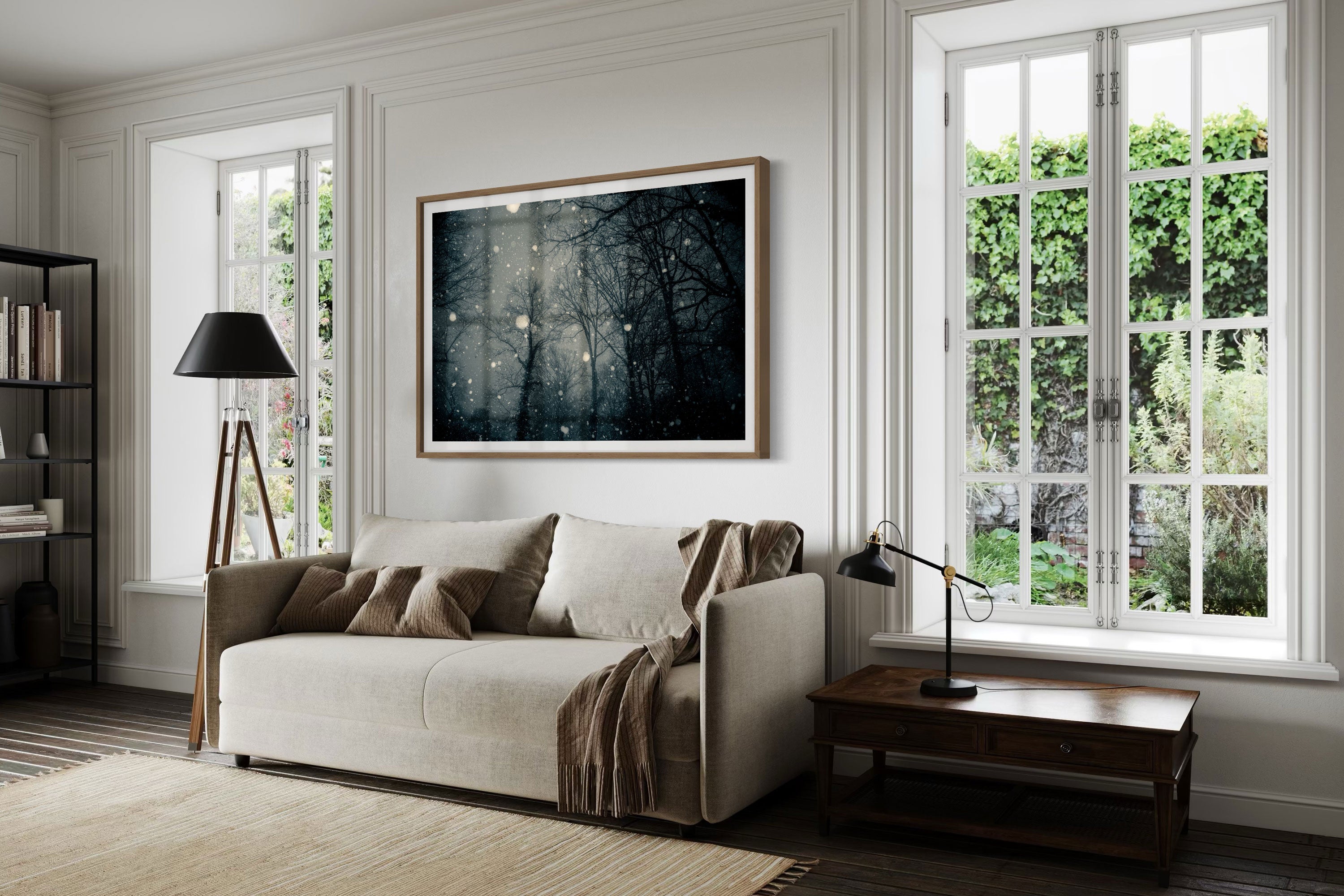 A living room with a framed fine art landscape photograph featuring snowfall in a forest.