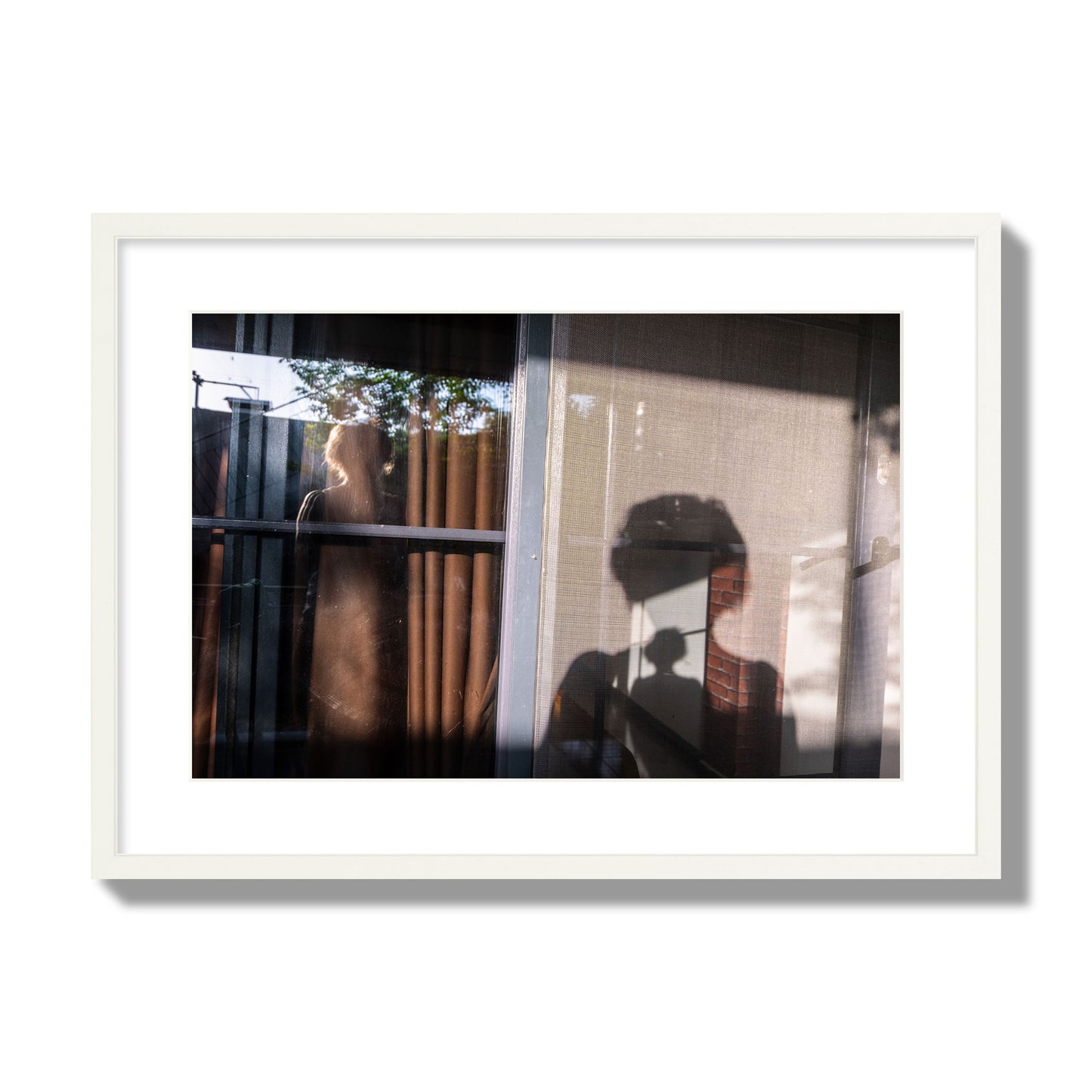 Fine art photograph of a person's silhouette against a window with curtains, archival pigment print, large size, white frame.