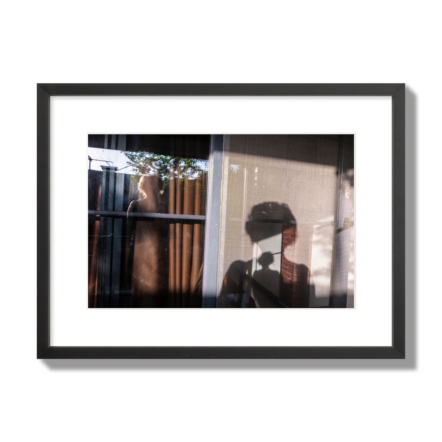 Fine art photograph of a person's silhouette against a window with curtains, archival pigment print, medium size, black frame.