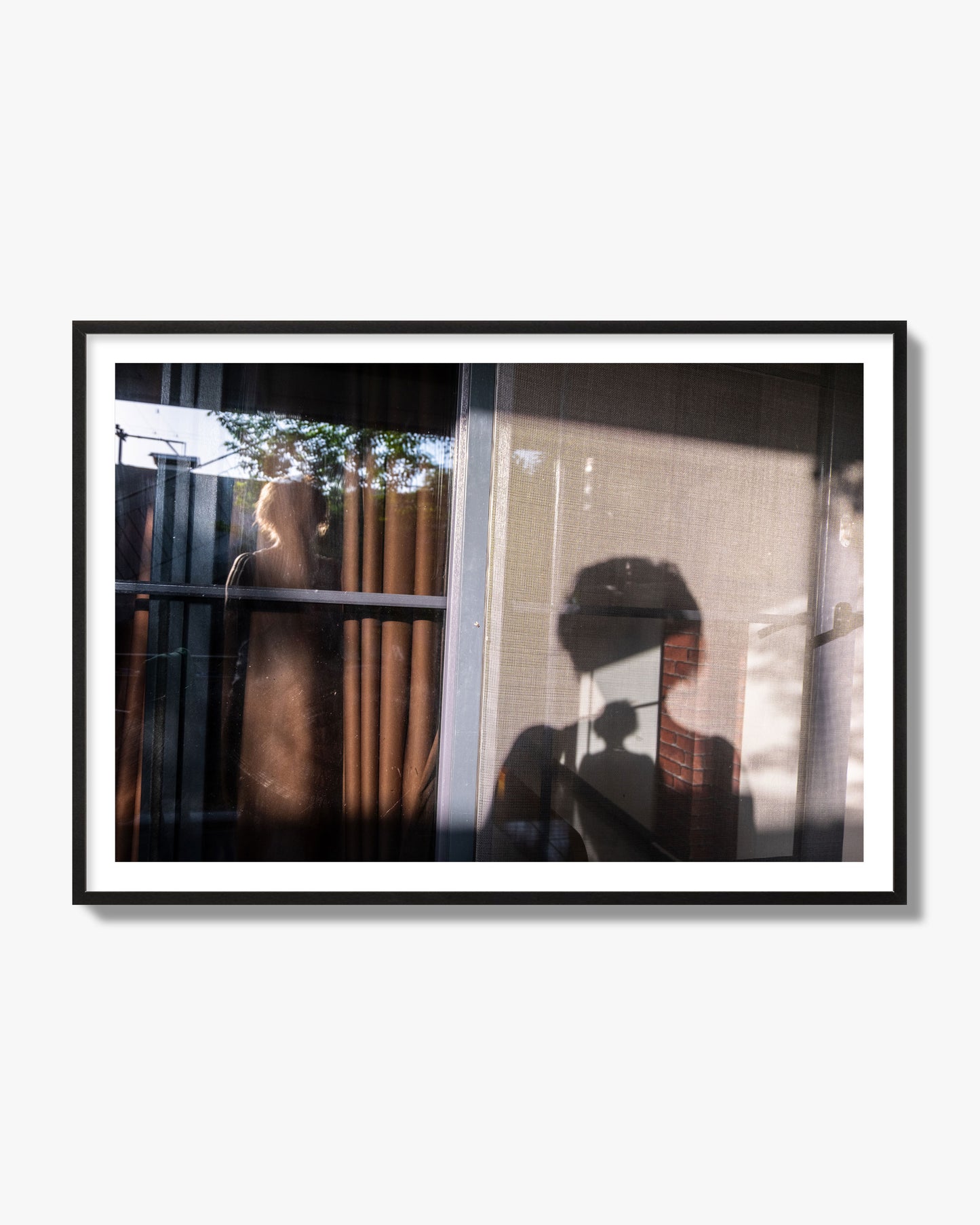 Fine art photograph of a person's silhouette against a window with curtains, archival pigment print, black frame.