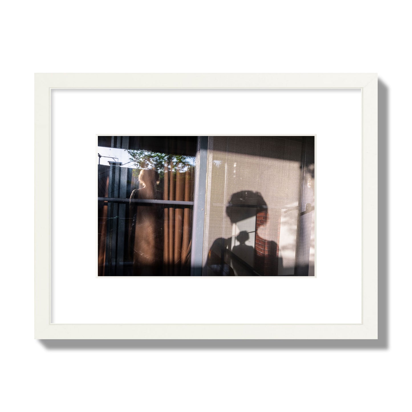 Fine art photograph of a person's silhouette against a window with curtains, archival pigment print, small size, white frame.