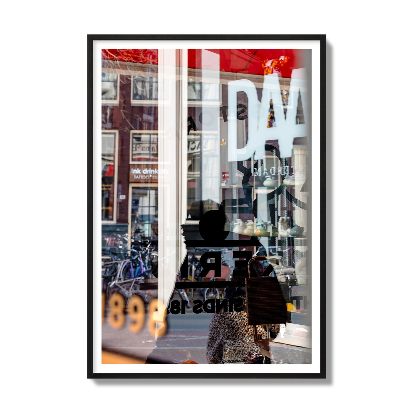 Fine art street photograph of a busy Amsterdam street scene with reflections, silhouettes, shoppers, and store signs. Archival pigment print, gallery size, black frame.