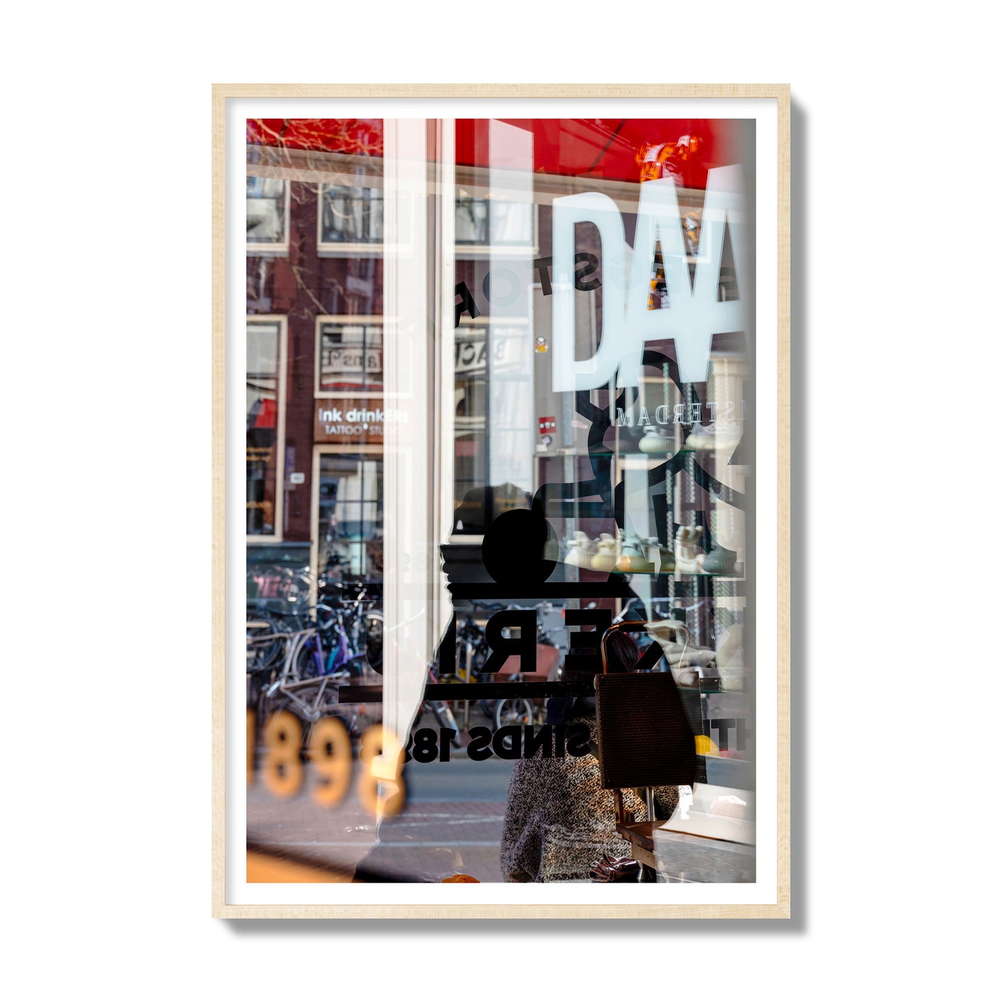 Fine art street photograph of a busy Amsterdam street scene with reflections, silhouettes, shoppers, and store signs. Archival pigment print, gallery size, natural wood frame.