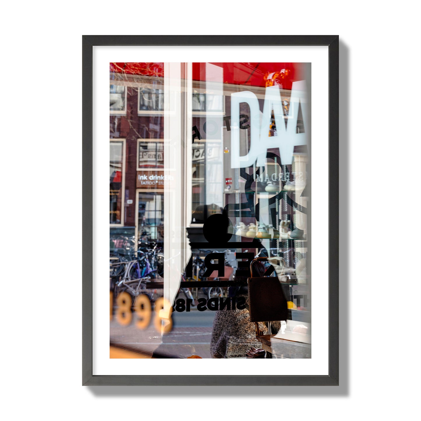 Fine art street photograph of a busy Amsterdam street scene with reflections, silhouettes, shoppers, and store signs. Archival pigment print, giant size, black frame.