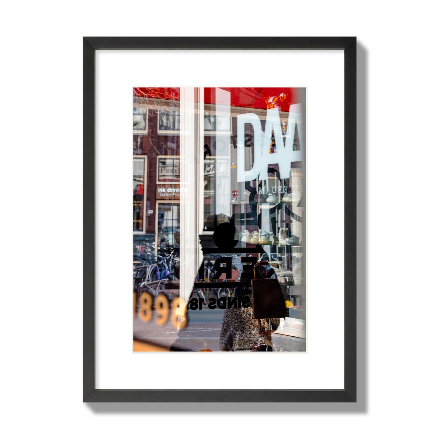 Fine art street photograph of a busy Amsterdam street scene with reflections, silhouettes, shoppers, and store signs. Archival pigment print, medium size, black frame.
