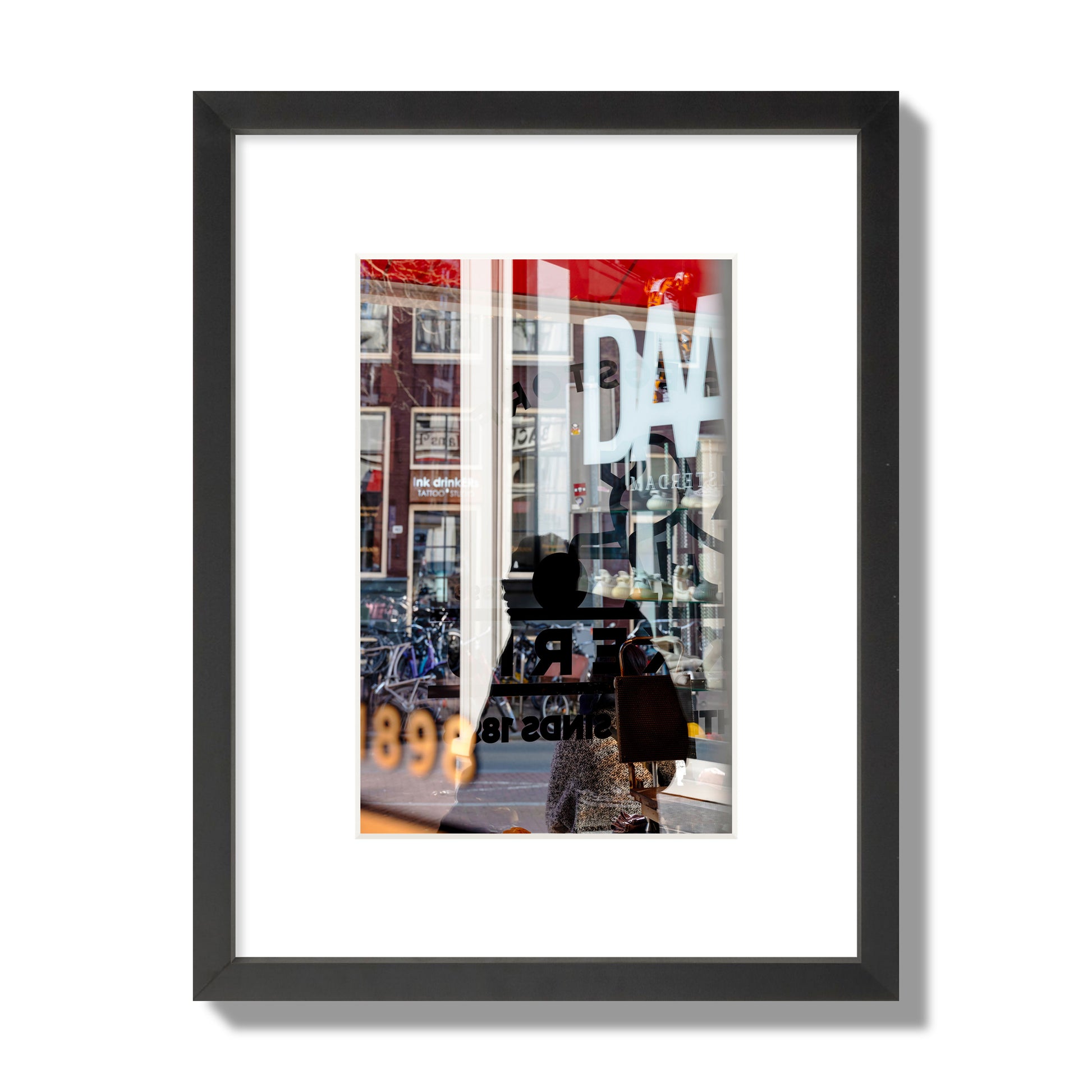 Fine art street photograph of a busy Amsterdam street scene with reflections, silhouettes, shoppers, and store signs. Archival pigment print, small size, black frame.