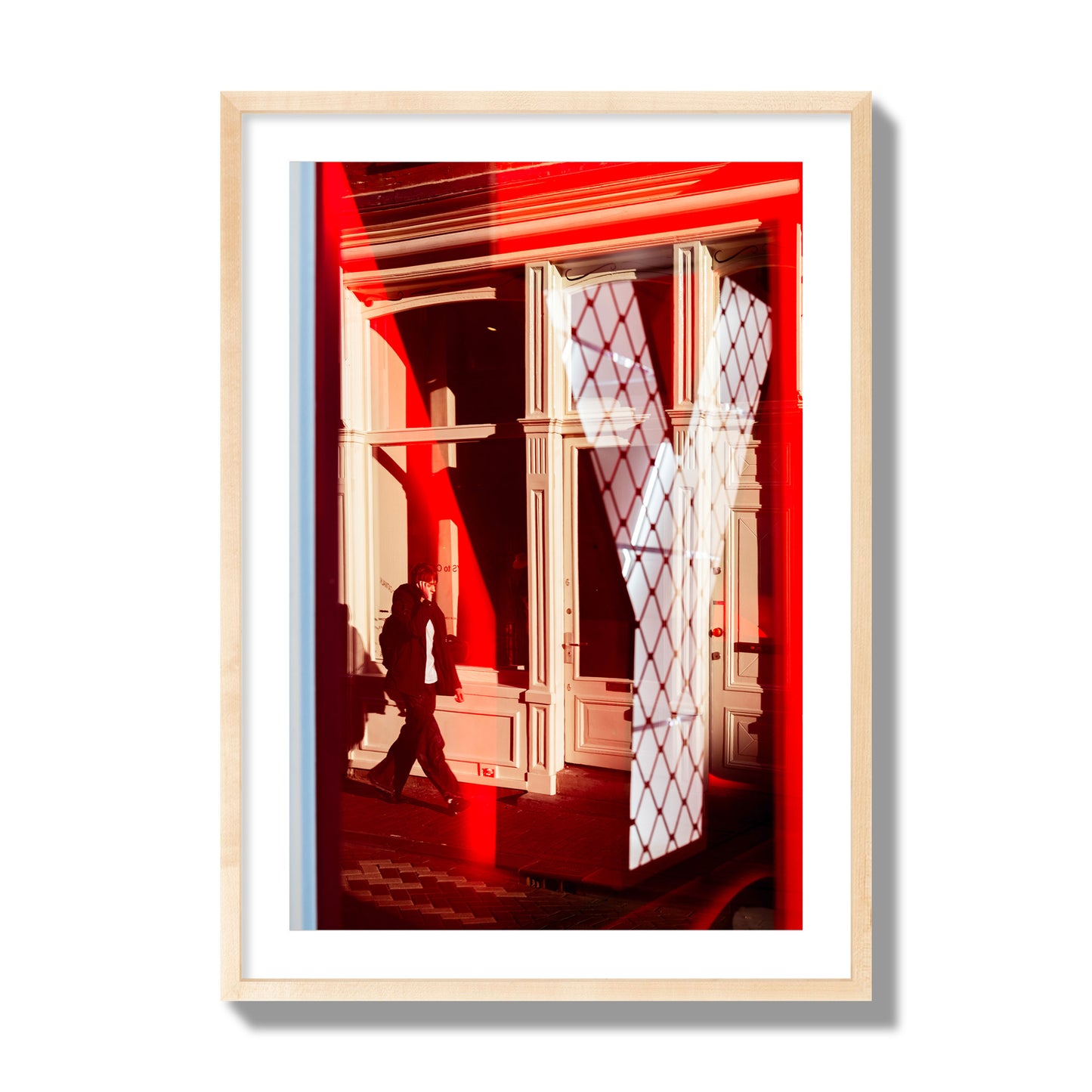 Fine art street photograph of an Amsterdam street scene showing bright red and white reflections of a large letter Y, a man walking, and multiple store fronts. Archival pigment print, giant size, natural wood frame.