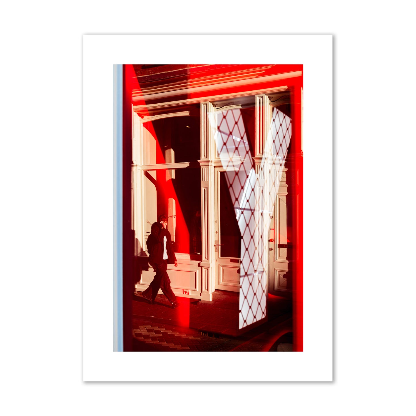 Fine art street photograph of an Amsterdam street scene showing bright red and white reflections of a large letter Y, a man walking, and multiple store fronts. Archival pigment print, giant size, unframed.