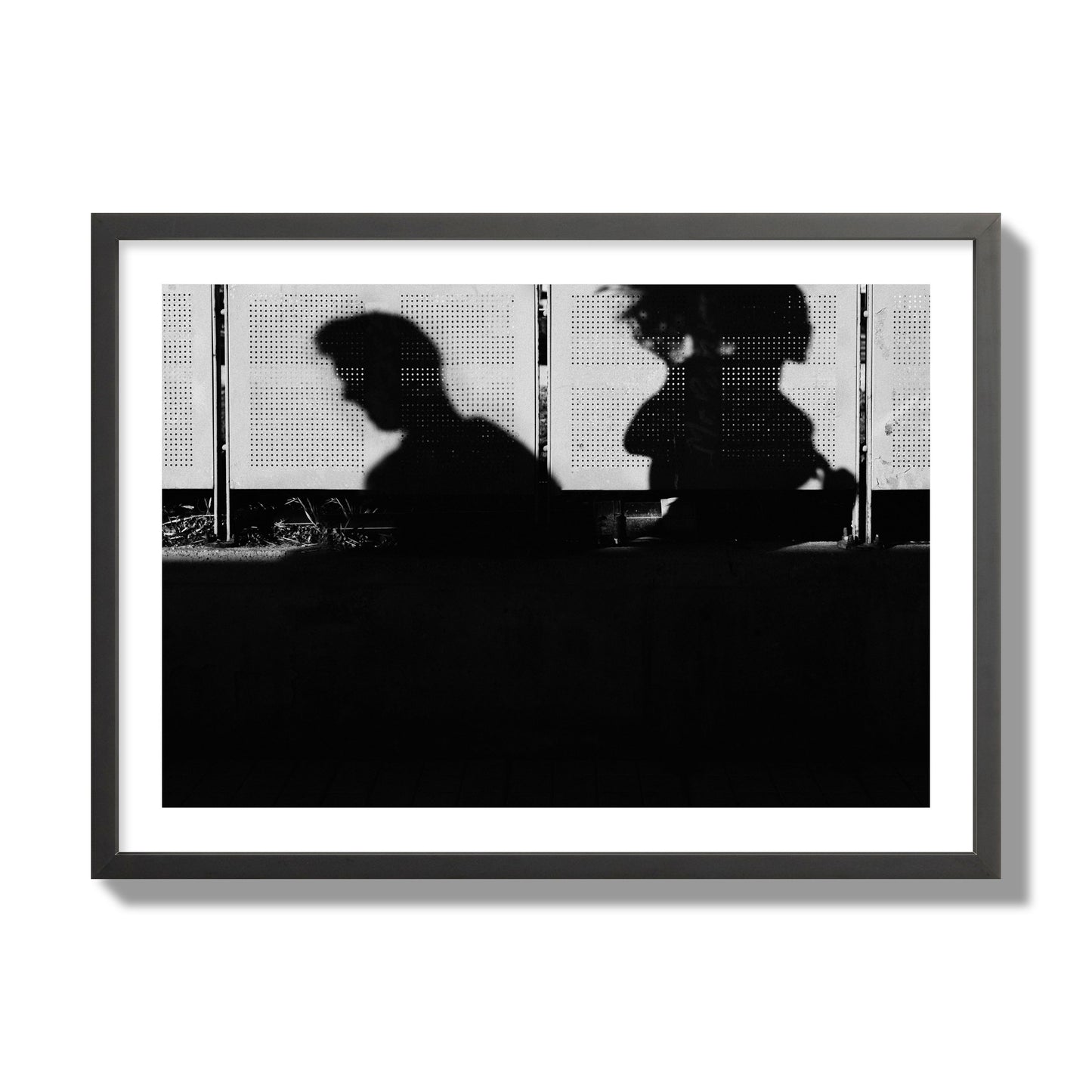 Fine art black and white street photography capturing the silhouettes of two individuals against a wall in Athens Greece, archival pigment print, giant size, black frame