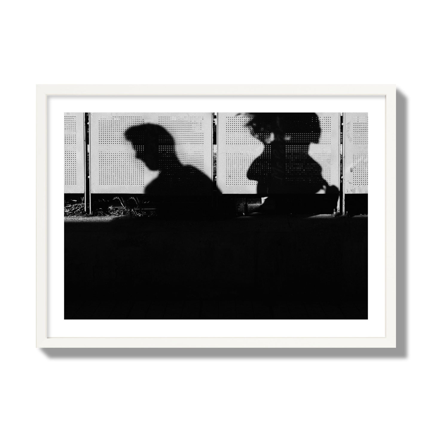 Fine art black and white street photography capturing the silhouettes of two individuals against a wall in Athens Greece, archival pigment print, giant size, white frame