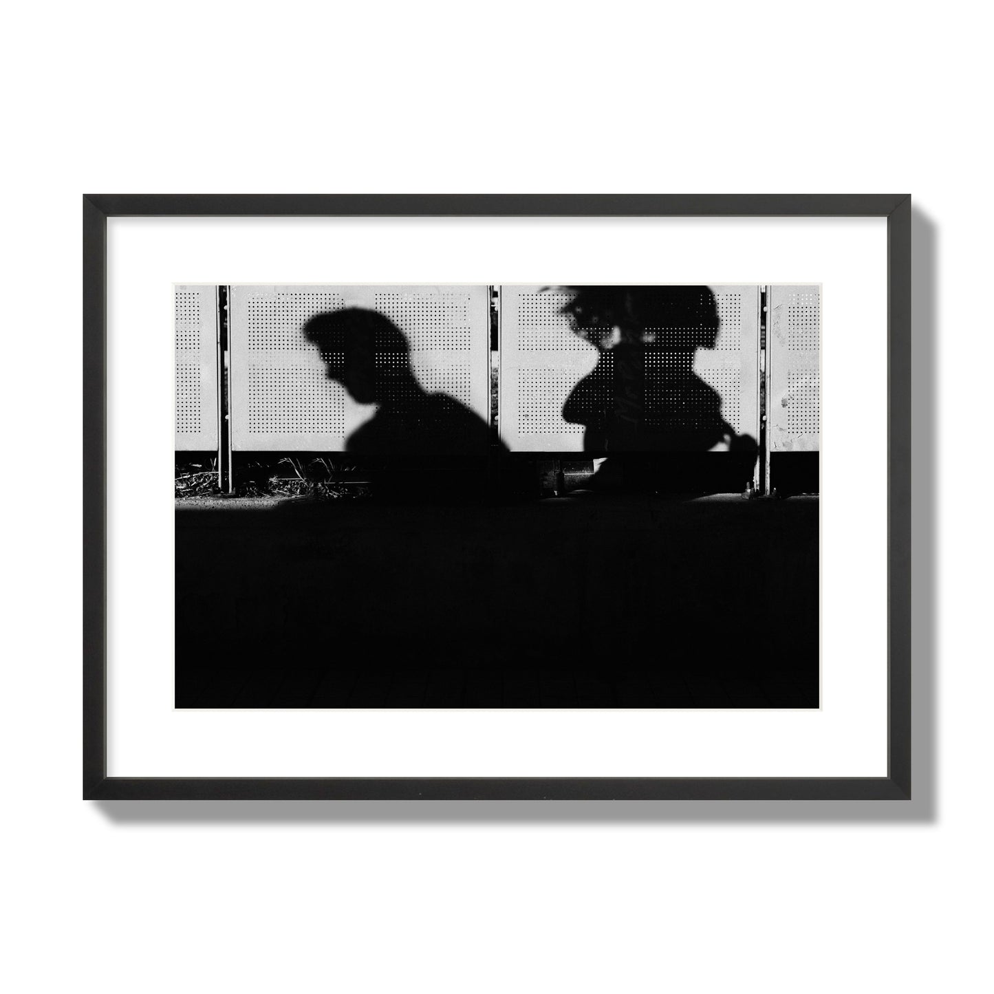 Fine art black and white street photography capturing the silhouettes of two individuals against a wall in Athens Greece, archival pigment print, large size, black frame