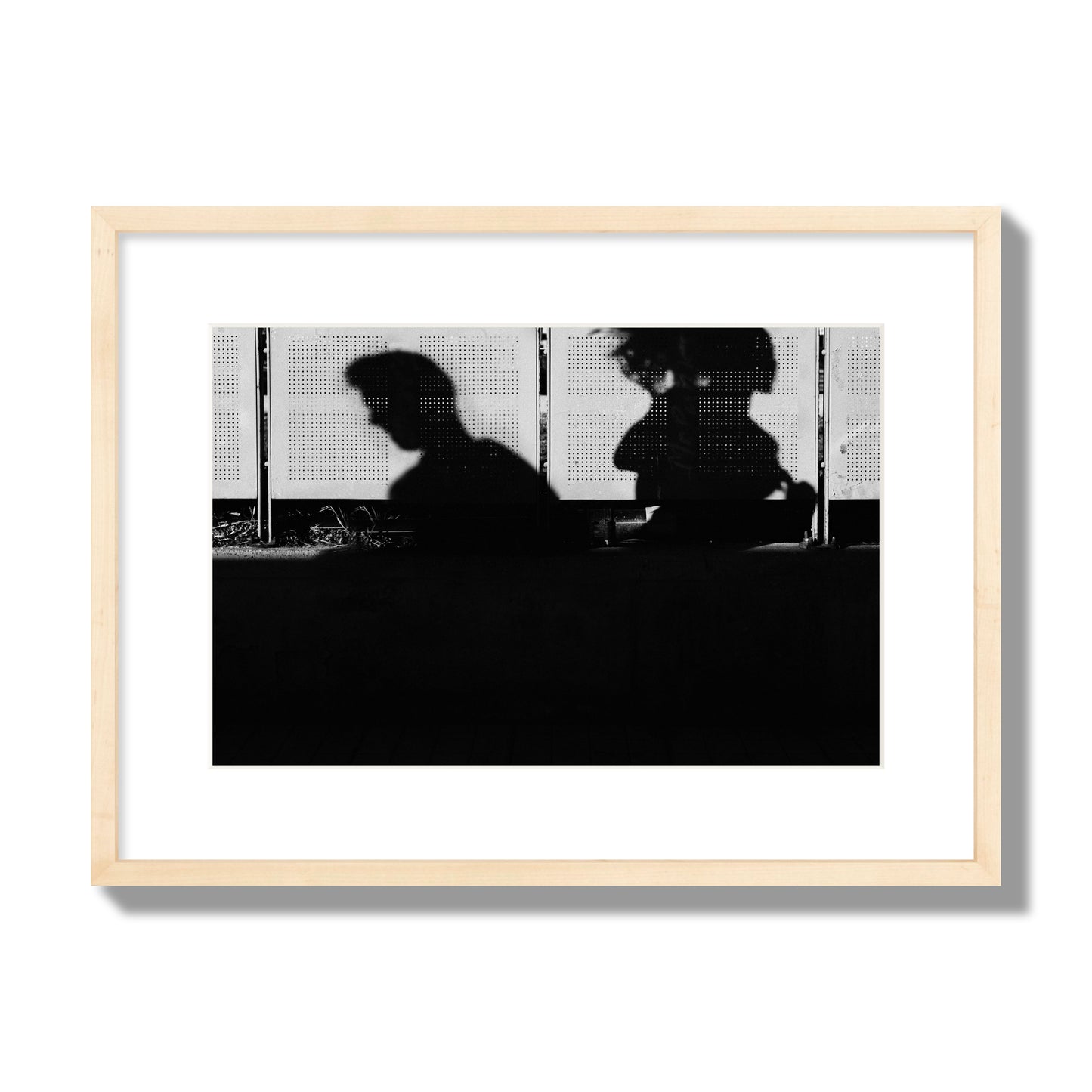 Fine art black and white street photography capturing the silhouettes of two individuals against a wall in Athens Greece, archival pigment print, medium size, natural wood frame