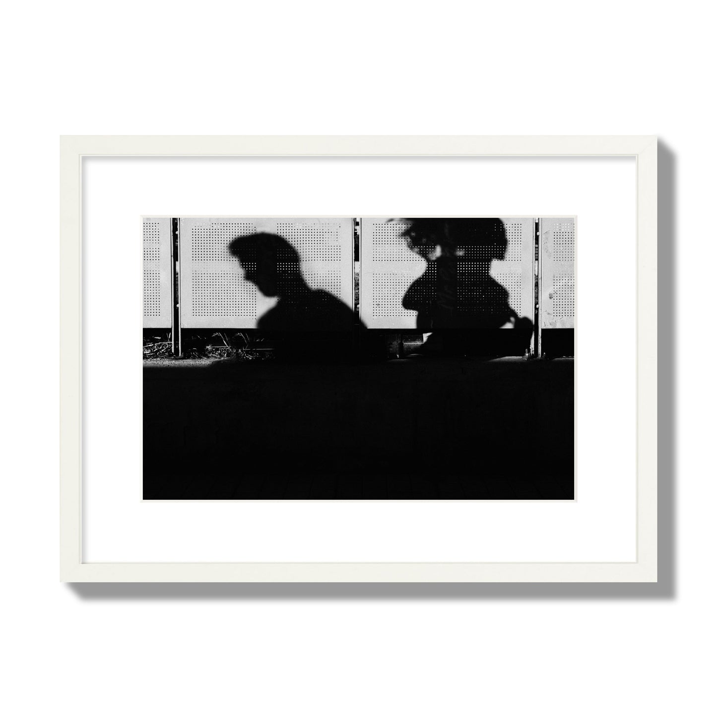 Fine art black and white street photography capturing the silhouettes of two individuals against a wall in Athens Greece, archival pigment print, medium size, white frame