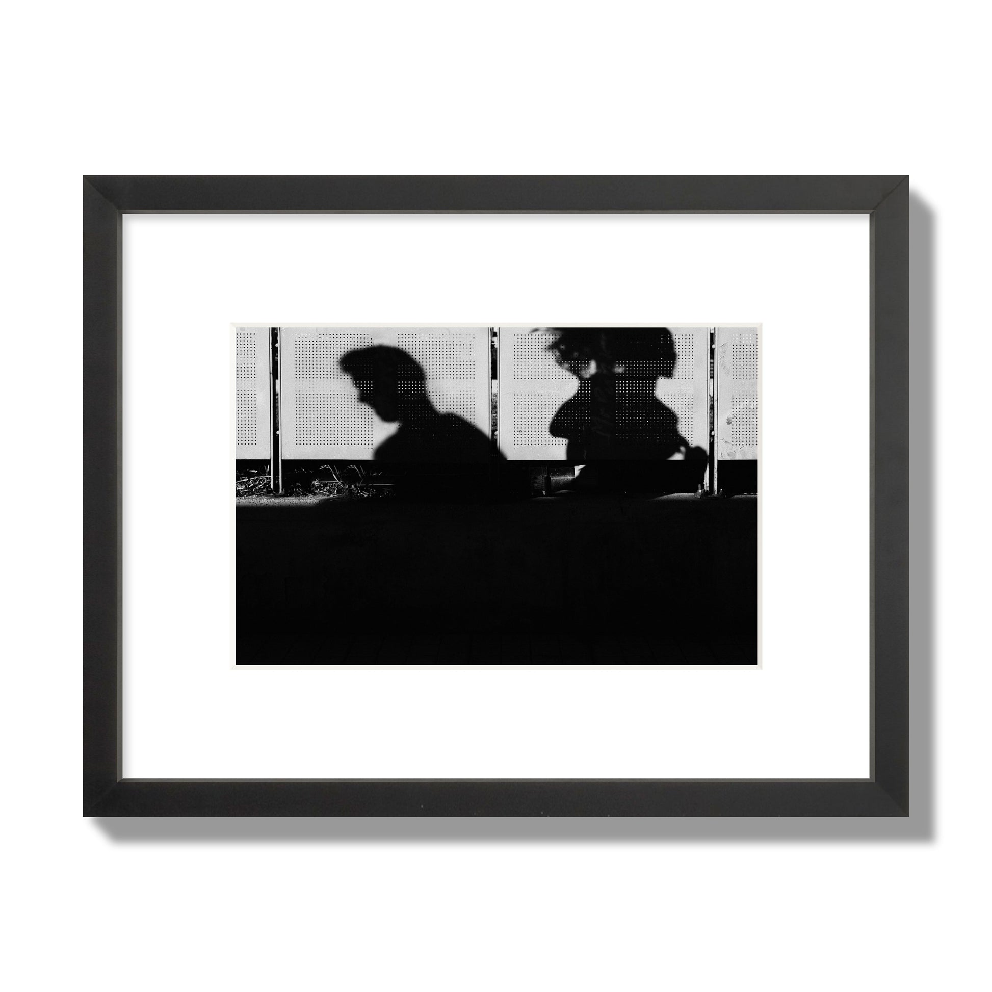 Fine art black and white street photography capturing the silhouettes of two individuals against a wall in Athens Greece, archival pigment print, small size, black frame