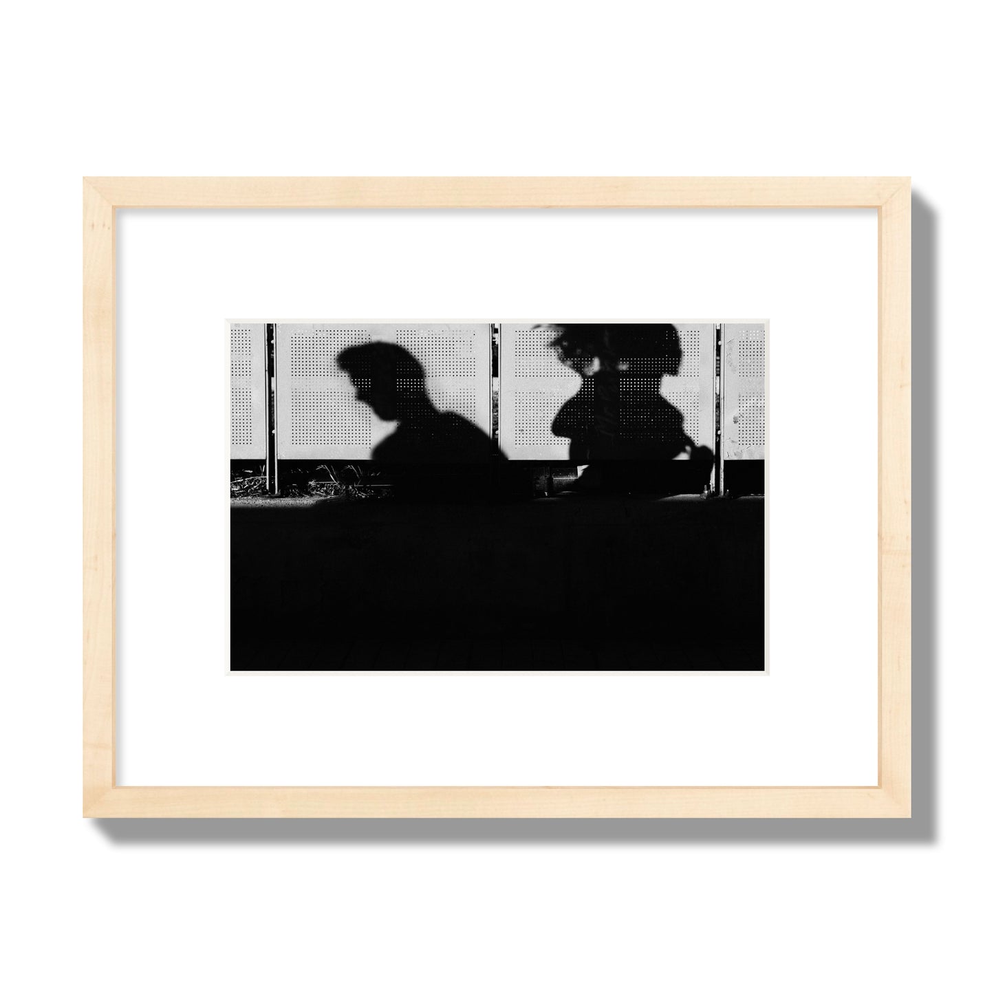Fine art black and white street photography capturing the silhouettes of two individuals against a wall in Athens Greece, archival pigment print, small size, natural wood frame