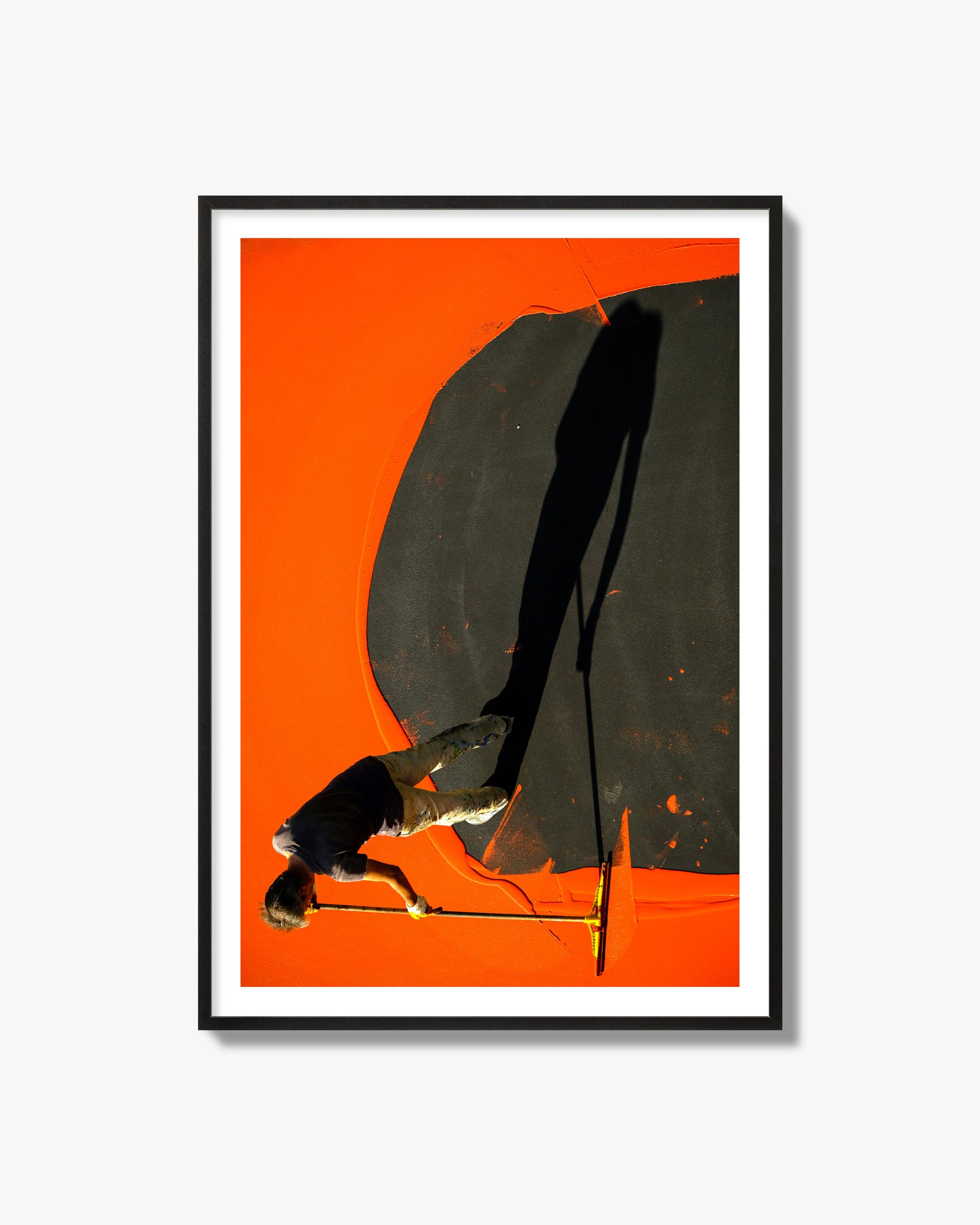 Fine art street photograph, overhead view of a man painting an orange rooftop, captured in vivid detail. Archival pigment print, black frame.