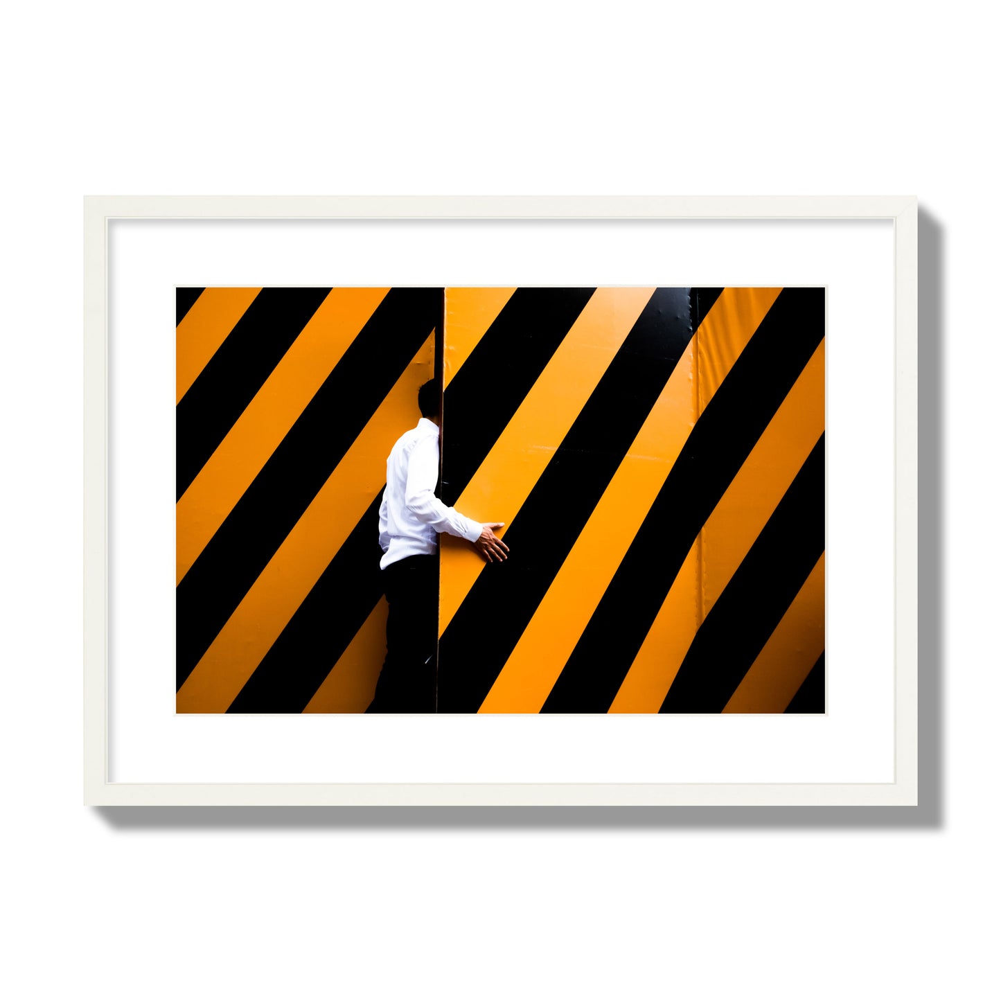 Fine art street photograph of a man opening an orange and black stripped construction door. Archival pigment print, large size, white frame.