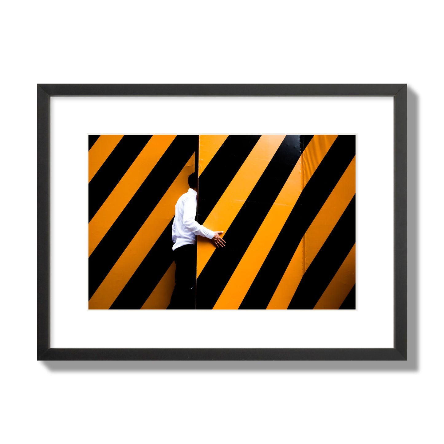 Fine art street photograph of a man opening an orange and black stripped construction door. Archival pigment print, medium size, black frame.