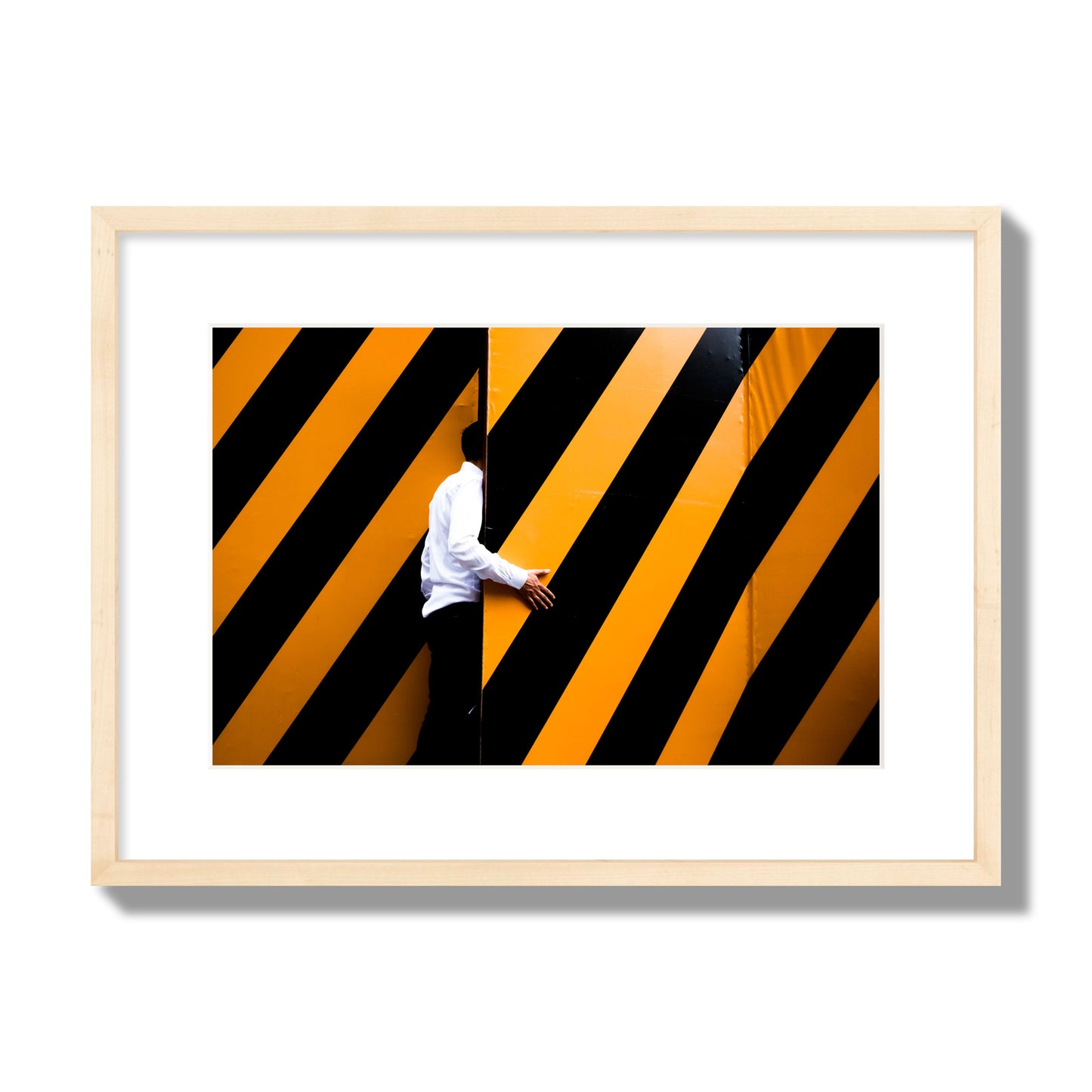 Fine art street photograph of a man opening an orange and black stripped construction door. Archival pigment print, medium size, natural wood frame.