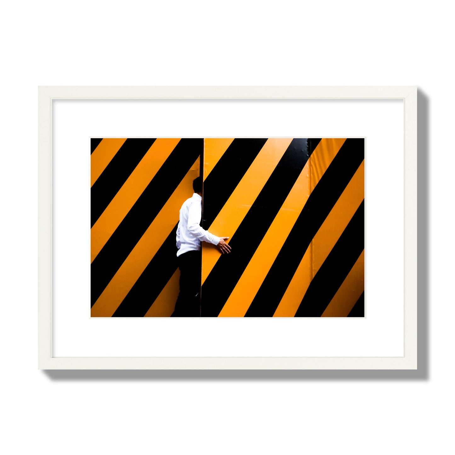 Fine art street photograph of a man opening an orange and black stripped construction door. Archival pigment print, medium size, white frame.