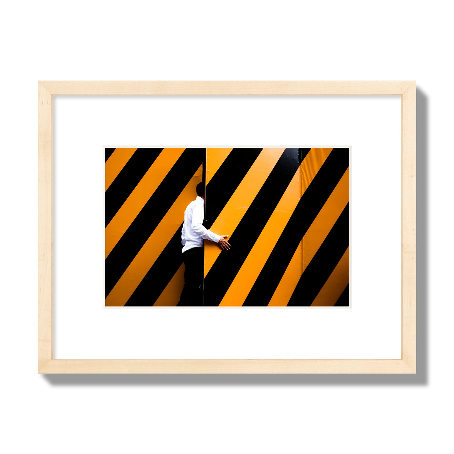 Fine art street photograph of a man opening an orange and black stripped construction door. Archival pigment print, small size, natural wood frame.