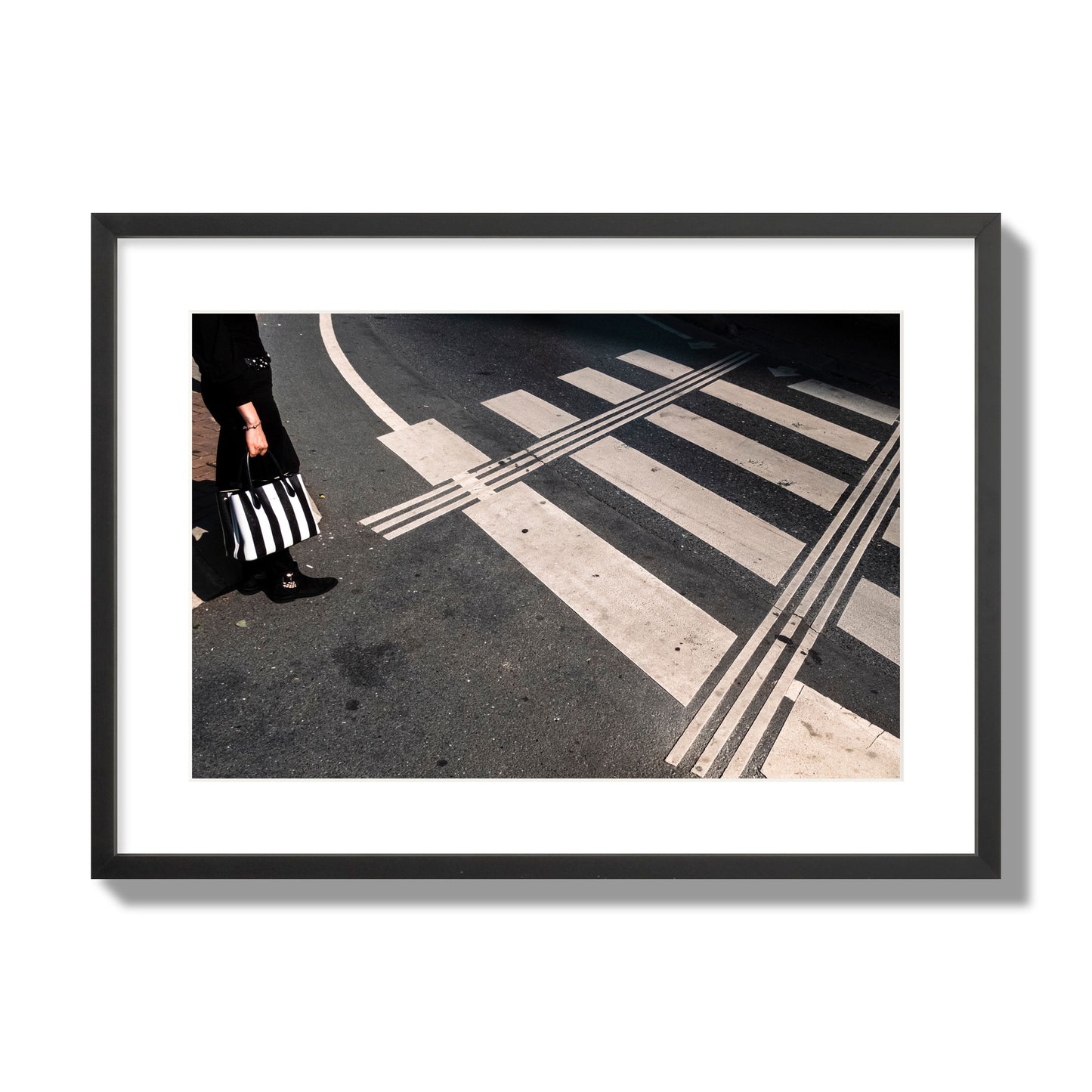 Fine art street photograph of a woman holding a black and white striped purse while crossing a black and white crosswalk. Archival pigment print, large size, black frame.