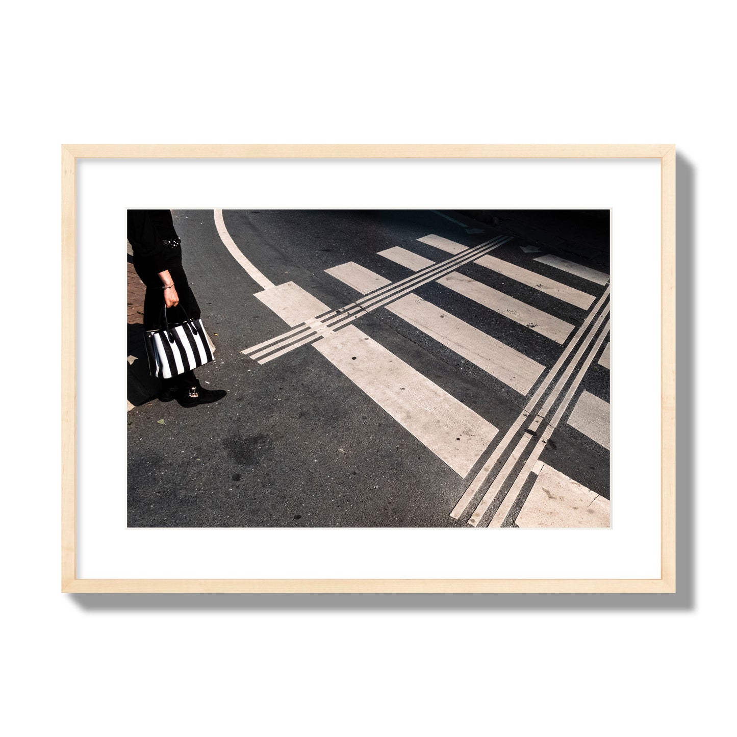 Fine art street photograph of a woman holding a black and white striped purse while crossing a black and white crosswalk. Archival pigment print, large size, natural wood frame.