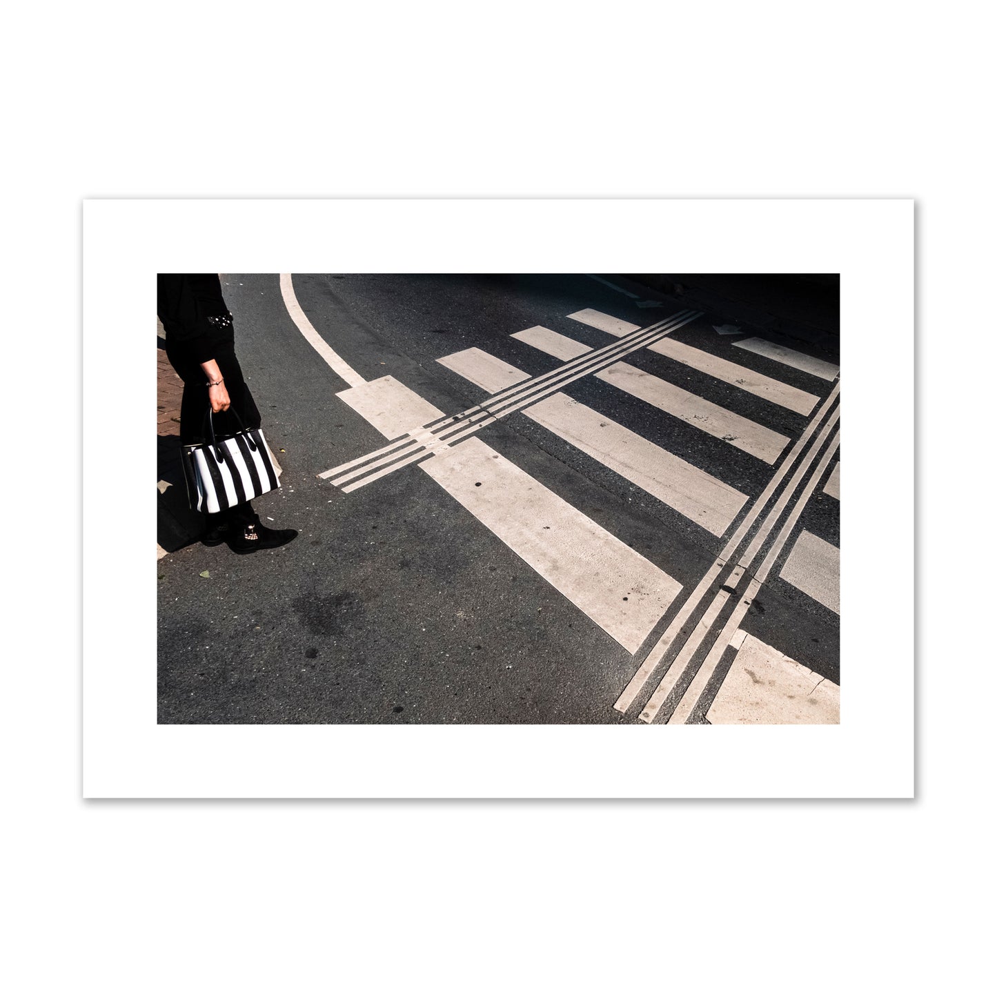 Fine art street photograph of a woman holding a black and white striped purse while crossing a black and white crosswalk. Archival pigment print, large size, unframed.