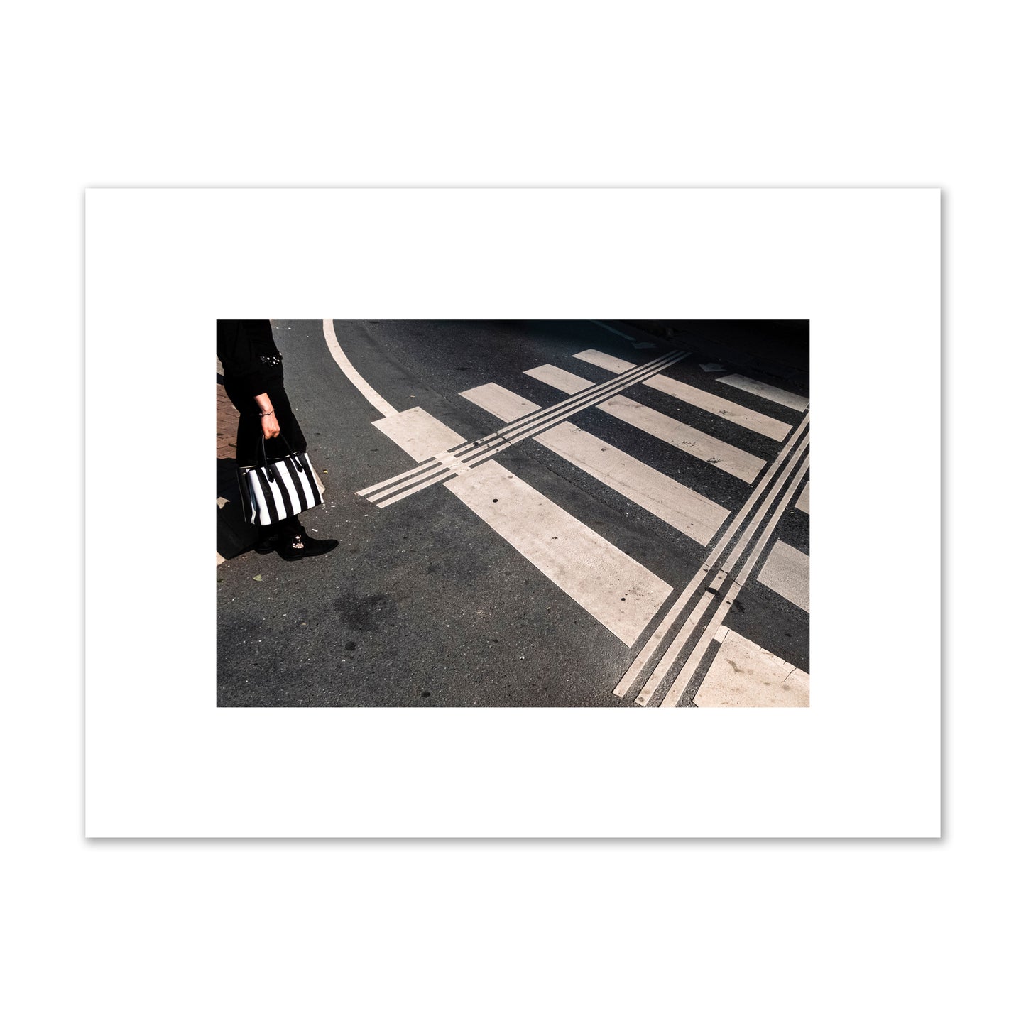 Fine art street photograph of a woman holding a black and white striped purse while crossing a black and white crosswalk. Archival pigment print, small size, unframed.