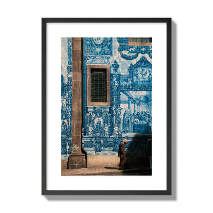 Fine art street photograph of an elderly man walking past traditional blue azulejo tile mural on a historic building in Lisbon, Portugal, archival pigment print, large size, black frame.
