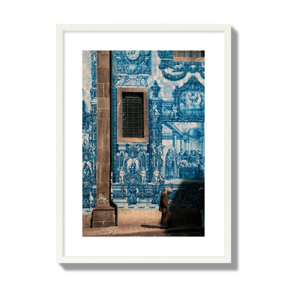 Fine art street photograph of an elderly man walking past traditional blue azulejo tile mural on a historic building in Lisbon, Portugal, archival pigment print, large size, white frame.