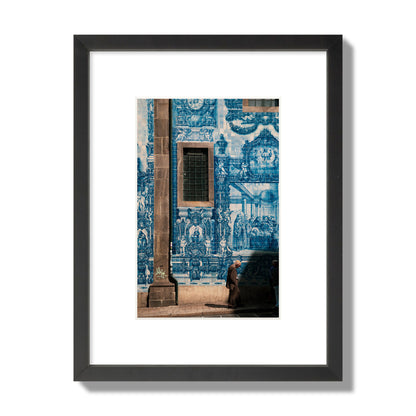 Fine art street photograph of an elderly man walking past traditional blue azulejo tile mural on a historic building in Lisbon, Portugal, archival pigment print, small size, black frame.