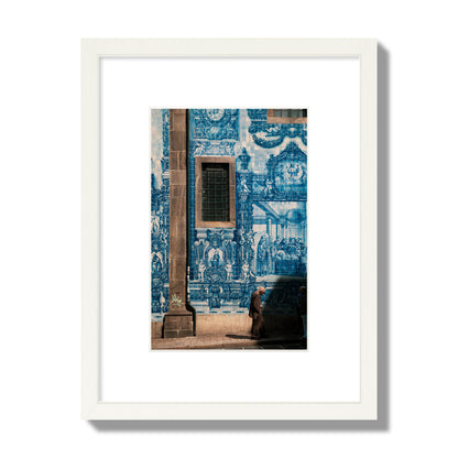 Fine art street photograph of an elderly man walking past traditional blue azulejo tile mural on a historic building in Lisbon, Portugal, archival pigment print, small size, white frame.