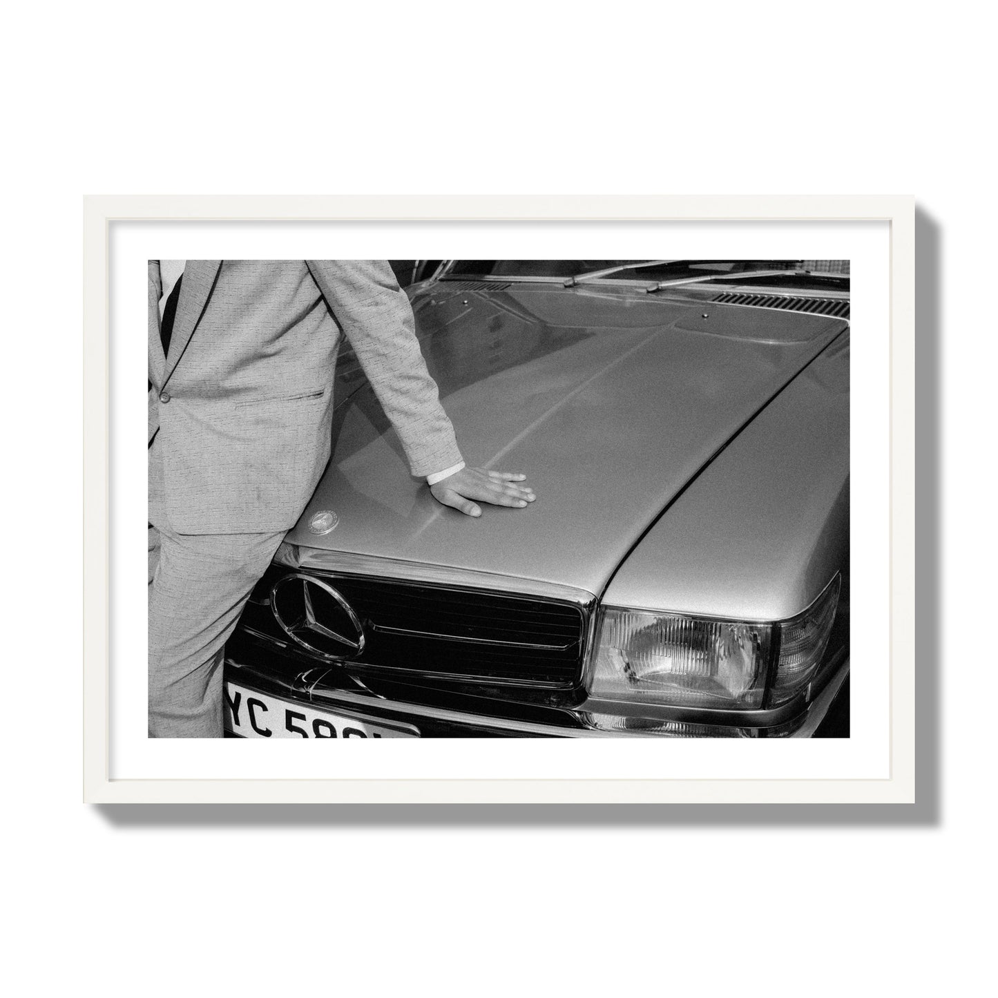 Fine art black & white photograph of a well dressed man leaning on a vintage Mercedes. Archival pigment print, giant size, white frame.