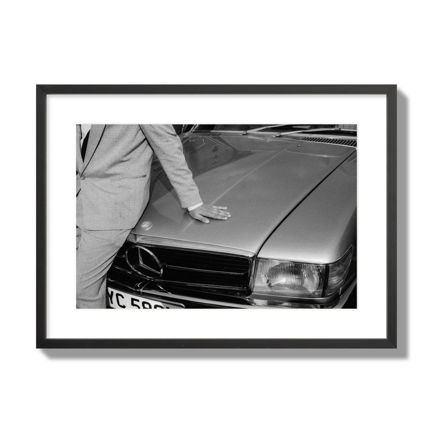 Fine art black & white photograph of a well dressed man leaning on a vintage Mercedes. Archival pigment print, large size, black frame.