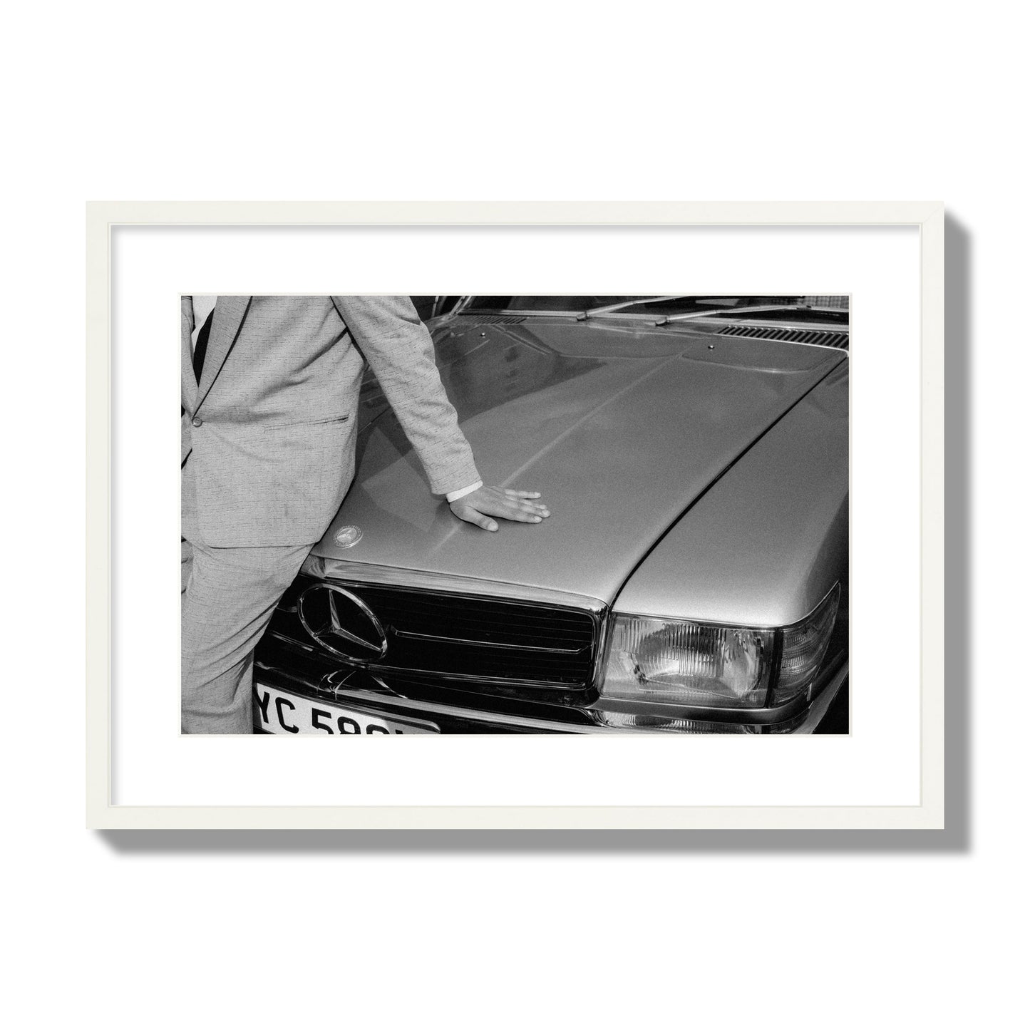 Fine art black & white photograph of a well dressed man leaning on a vintage Mercedes. Archival pigment print, large size, white frame.