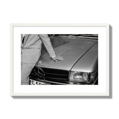 Fine art black & white photograph of a well dressed man leaning on a vintage Mercedes. Archival pigment print, large size, white frame.