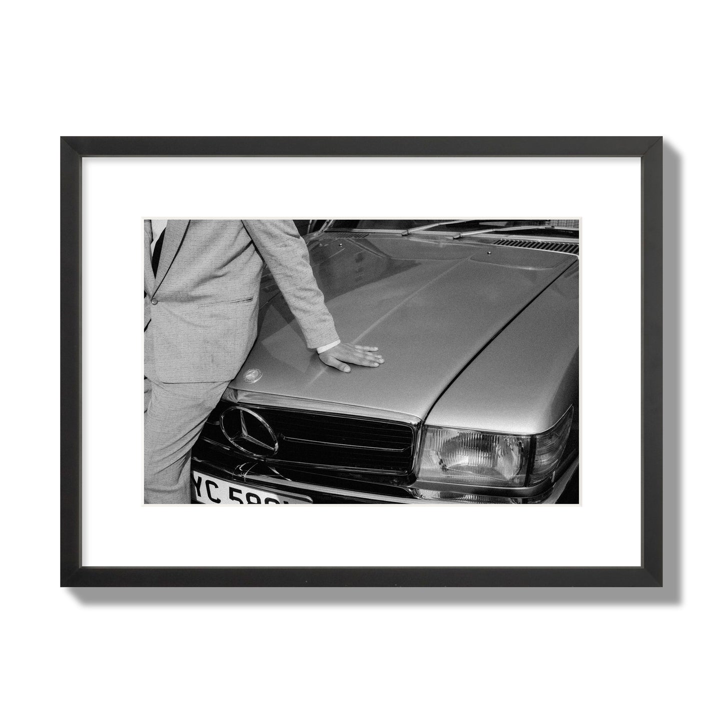 Fine art black & white photograph of a well dressed man leaning on a vintage Mercedes. Archival pigment print, medium size, black frame.