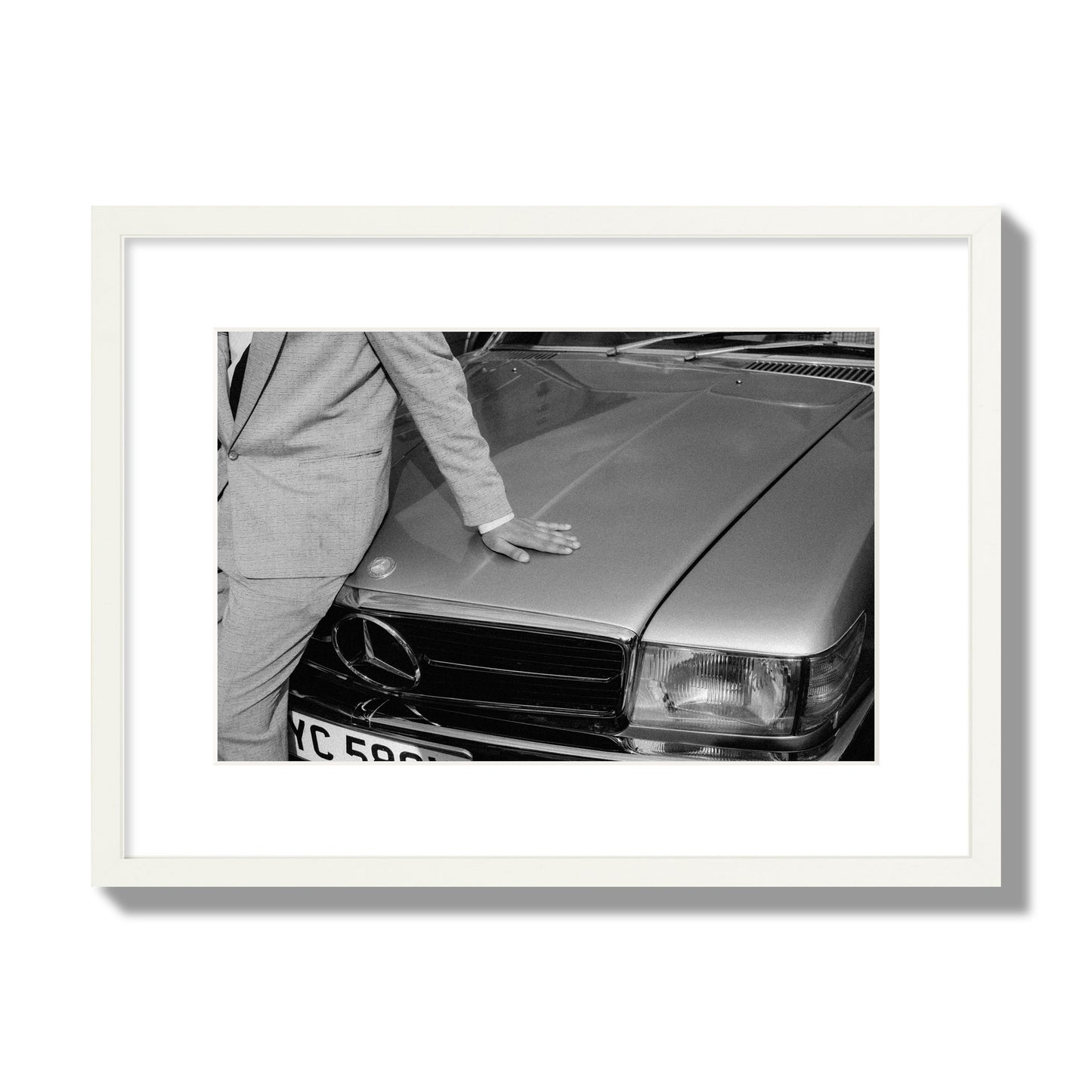 Fine art black & white photograph of a well dressed man leaning on a vintage Mercedes. Archival pigment print, medium size, white frame.