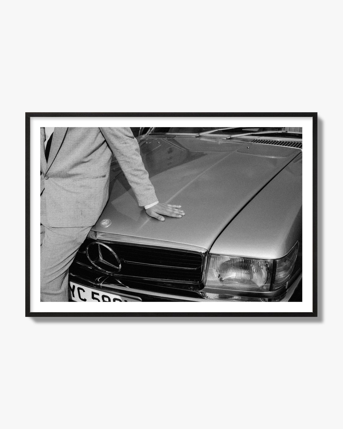 Fine art black & white photograph of a well dressed man leaning on a vintage Mercedes. Archival pigment print, black frame.