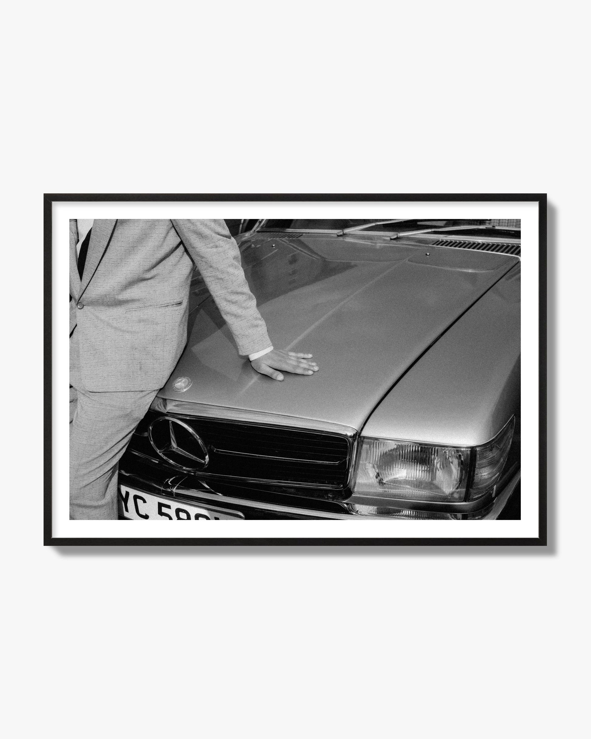Fine art black & white photograph of a well dressed man leaning on a vintage Mercedes. Archival pigment print, black frame.