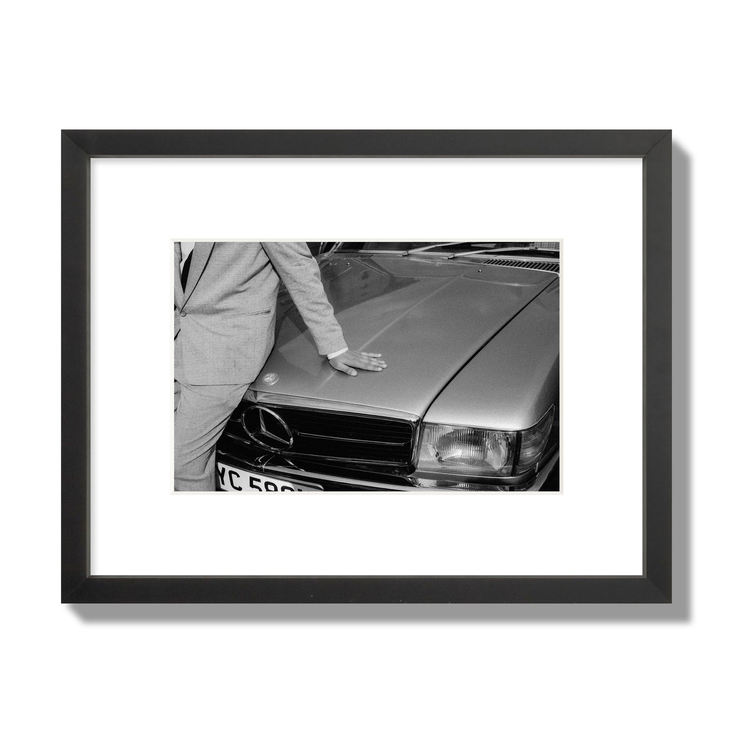 Fine art black & white photograph of a well dressed man leaning on a vintage Mercedes. Archival pigment print, small size, black frame.